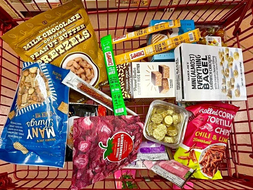 An overhead view of Trader Joe's snacks in a red shopping cart.