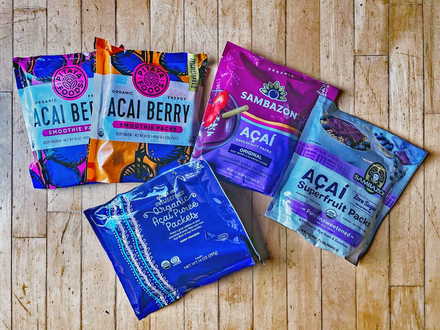 five packets of frozen acai from the grocery store on a wooden surface