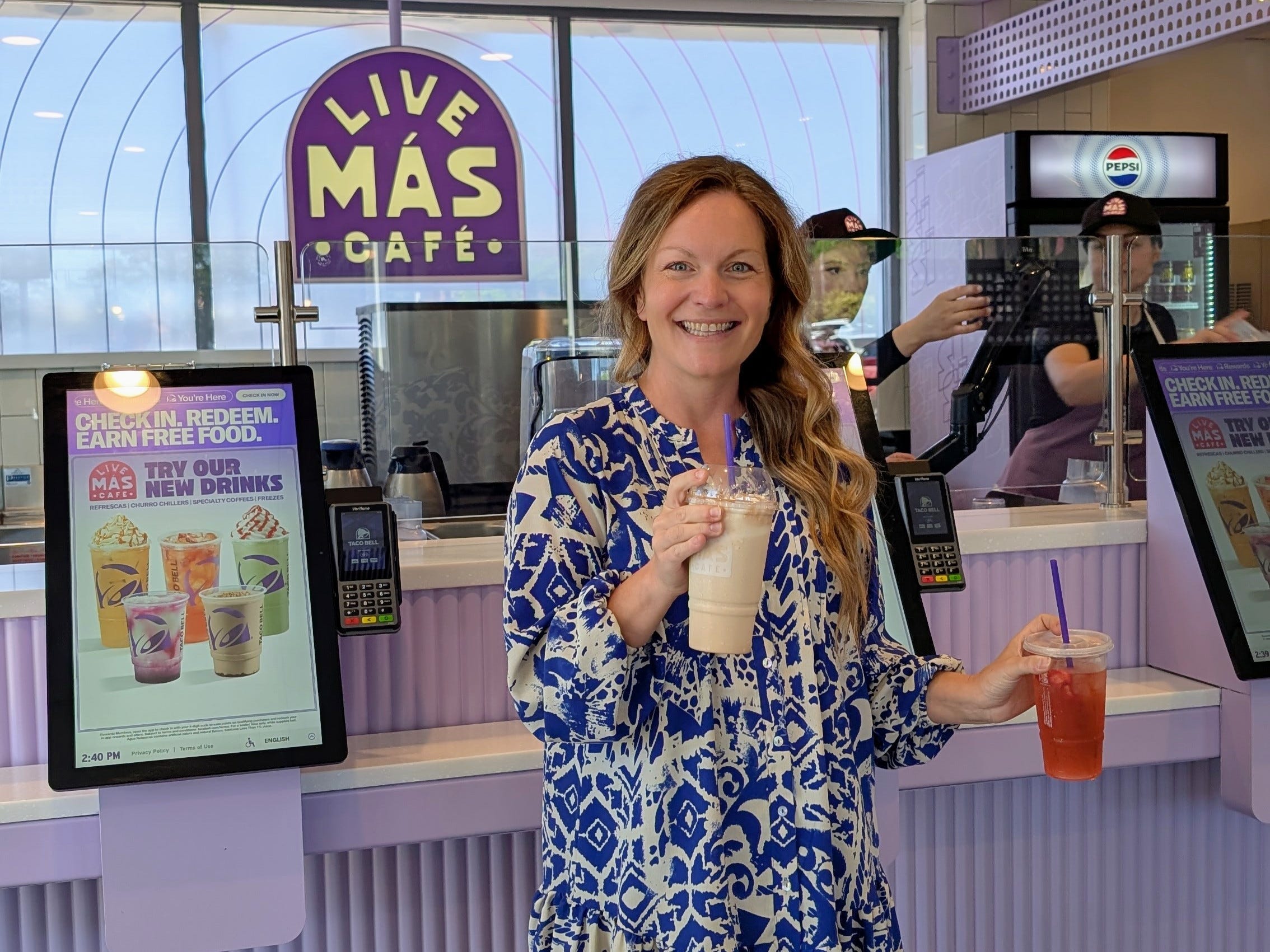 Author Michelle Stansbury smiling in Taco Bell Live Mas Cafe with drinks in each hand