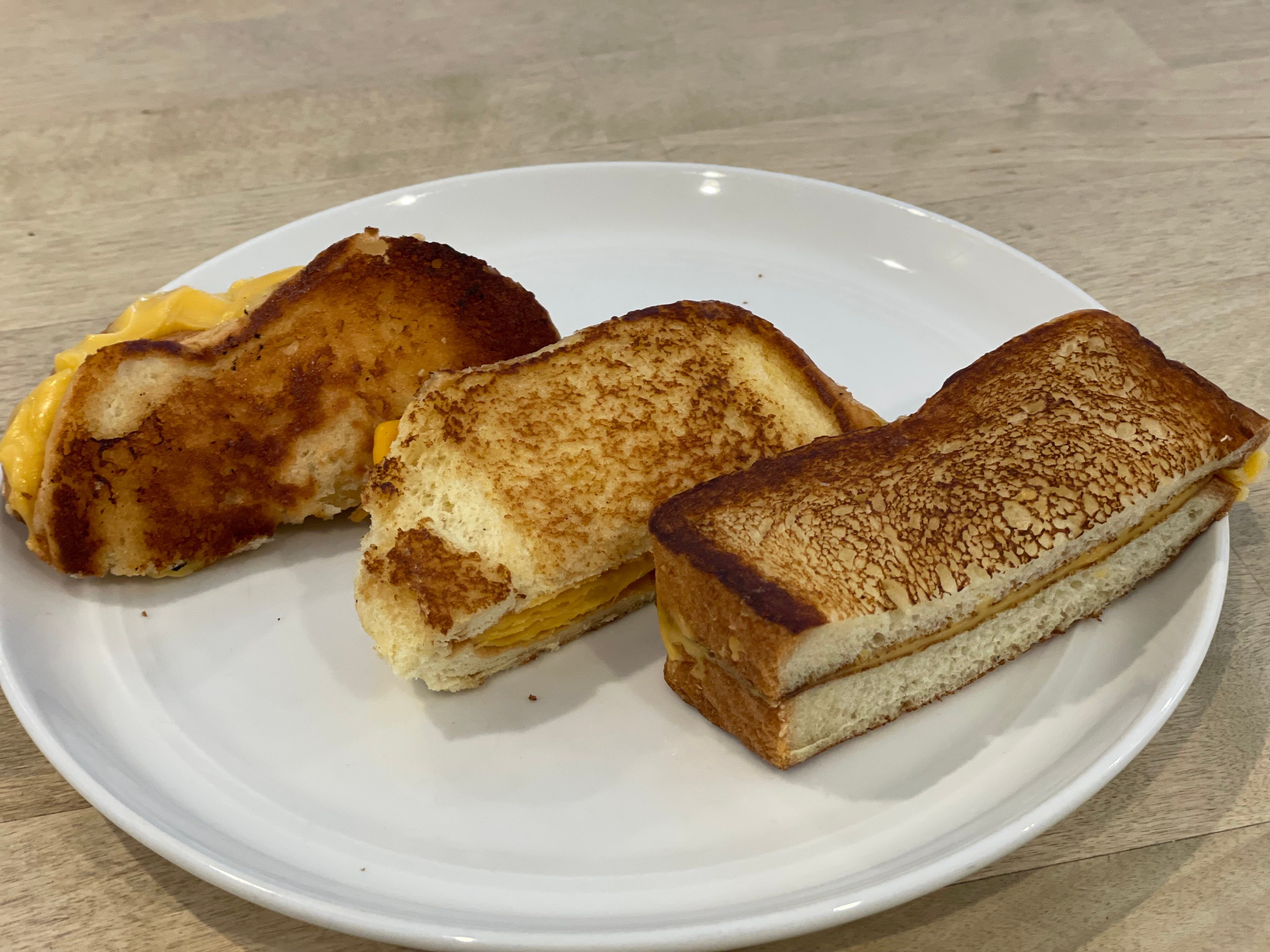 Half of each of the author's grilled cheese sandwiches from Five Guys, Shake Shack, and Sonic arranged on a plate.