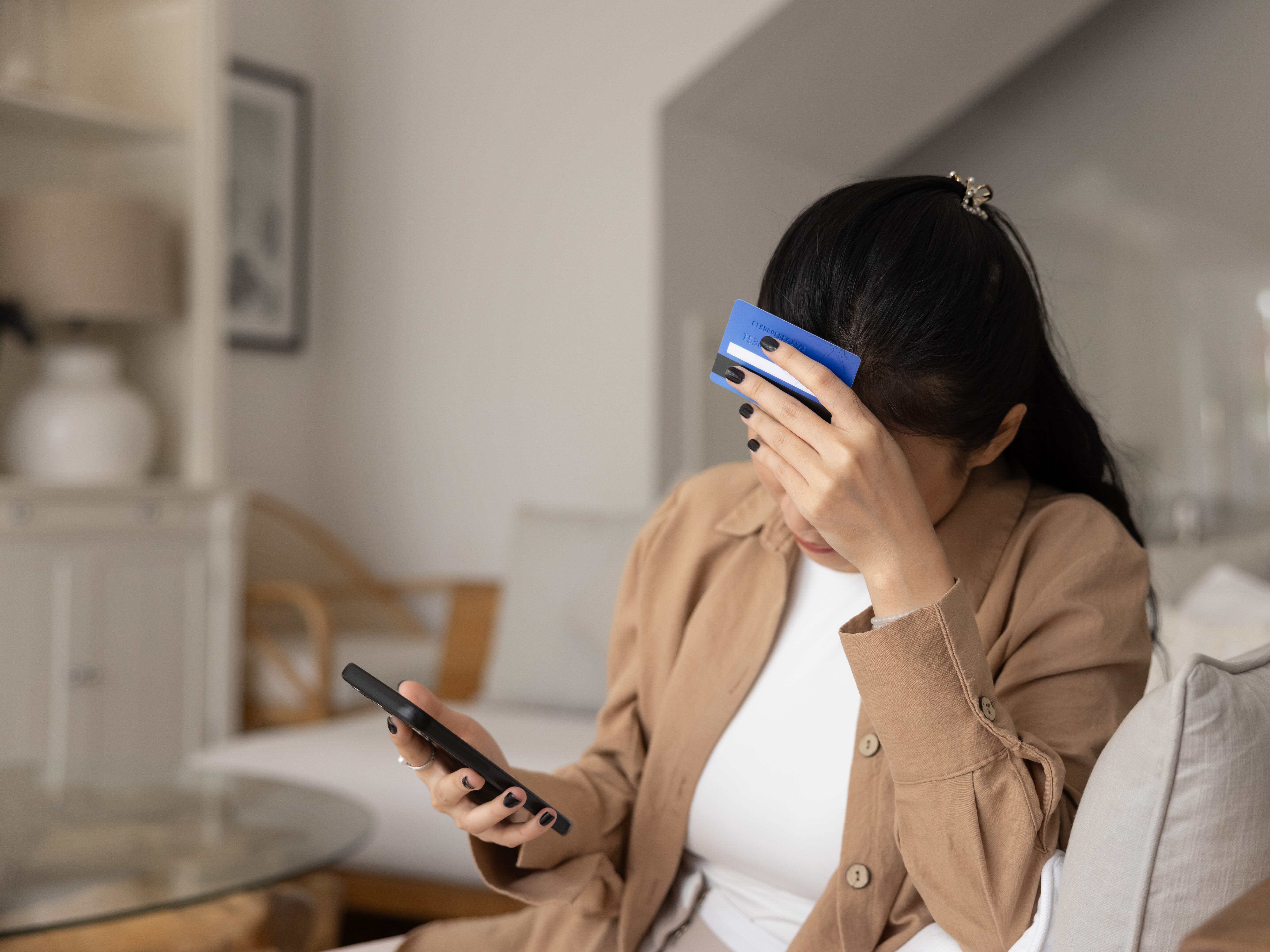 a woman looking at her phone while resting credit card on her head
