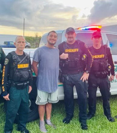 A man in custody stands between two sheriffs.