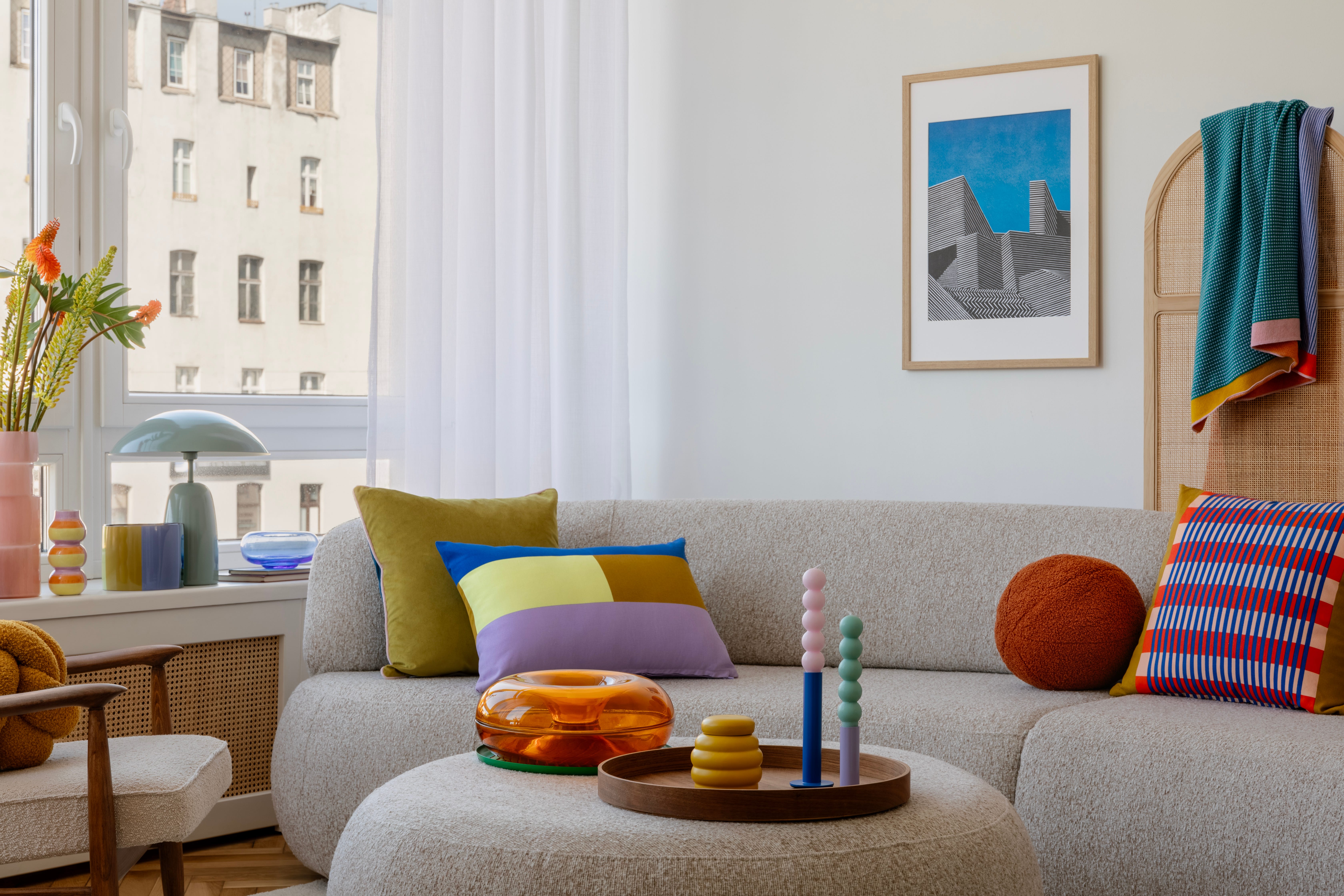 Living room with colorful patterned pillows, white walls, curved boucle couch