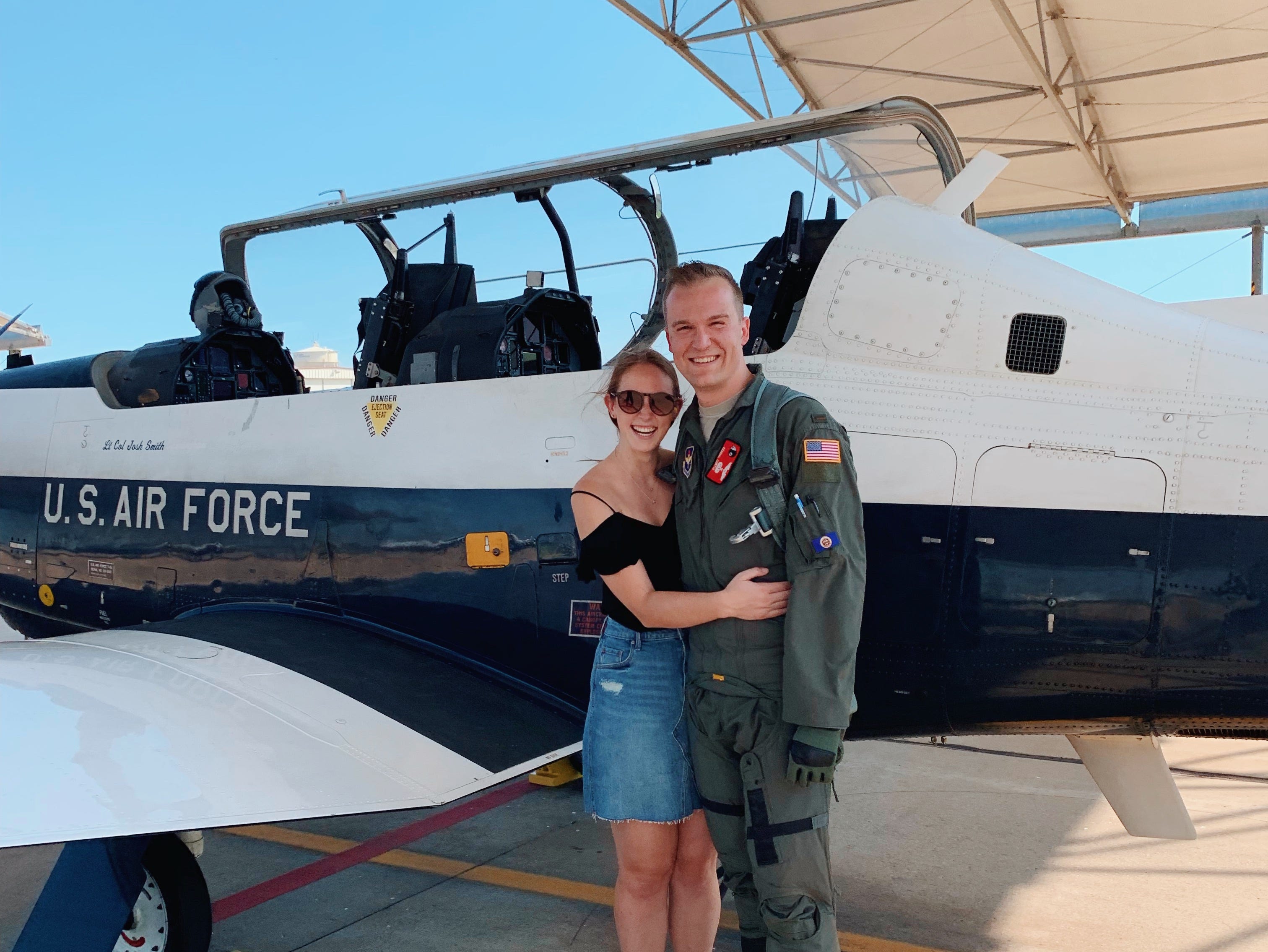 Allie Hubers hugging partner who is in an Air Force uniform in front of plane