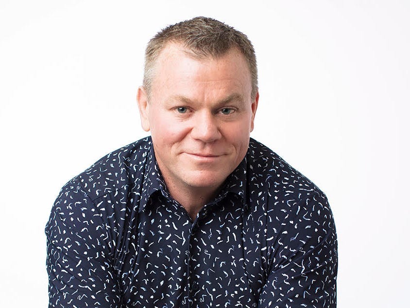 headshot of a man in a blue shirt with a white background