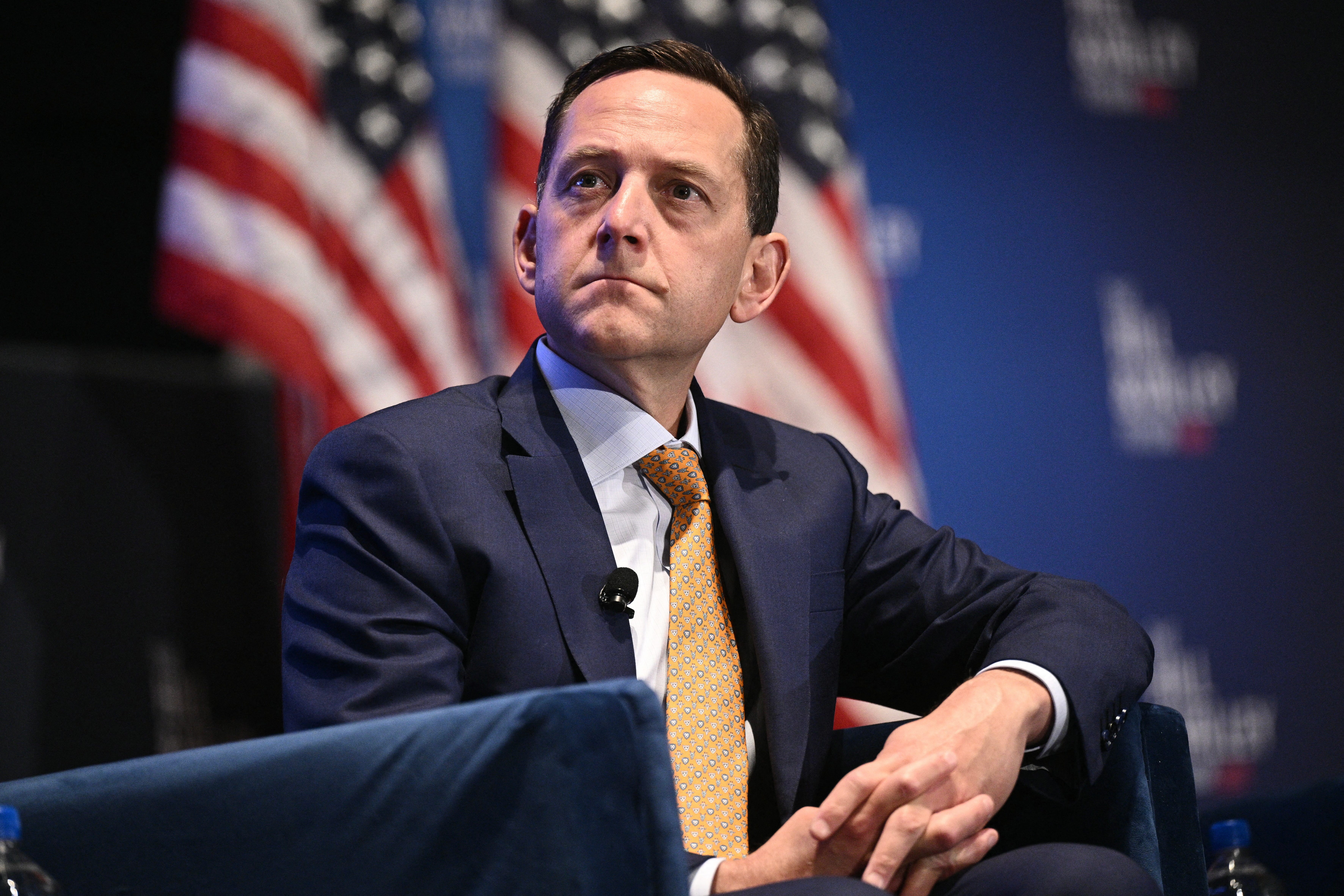 David Friedberg in a suit, seated in front of two US flags.