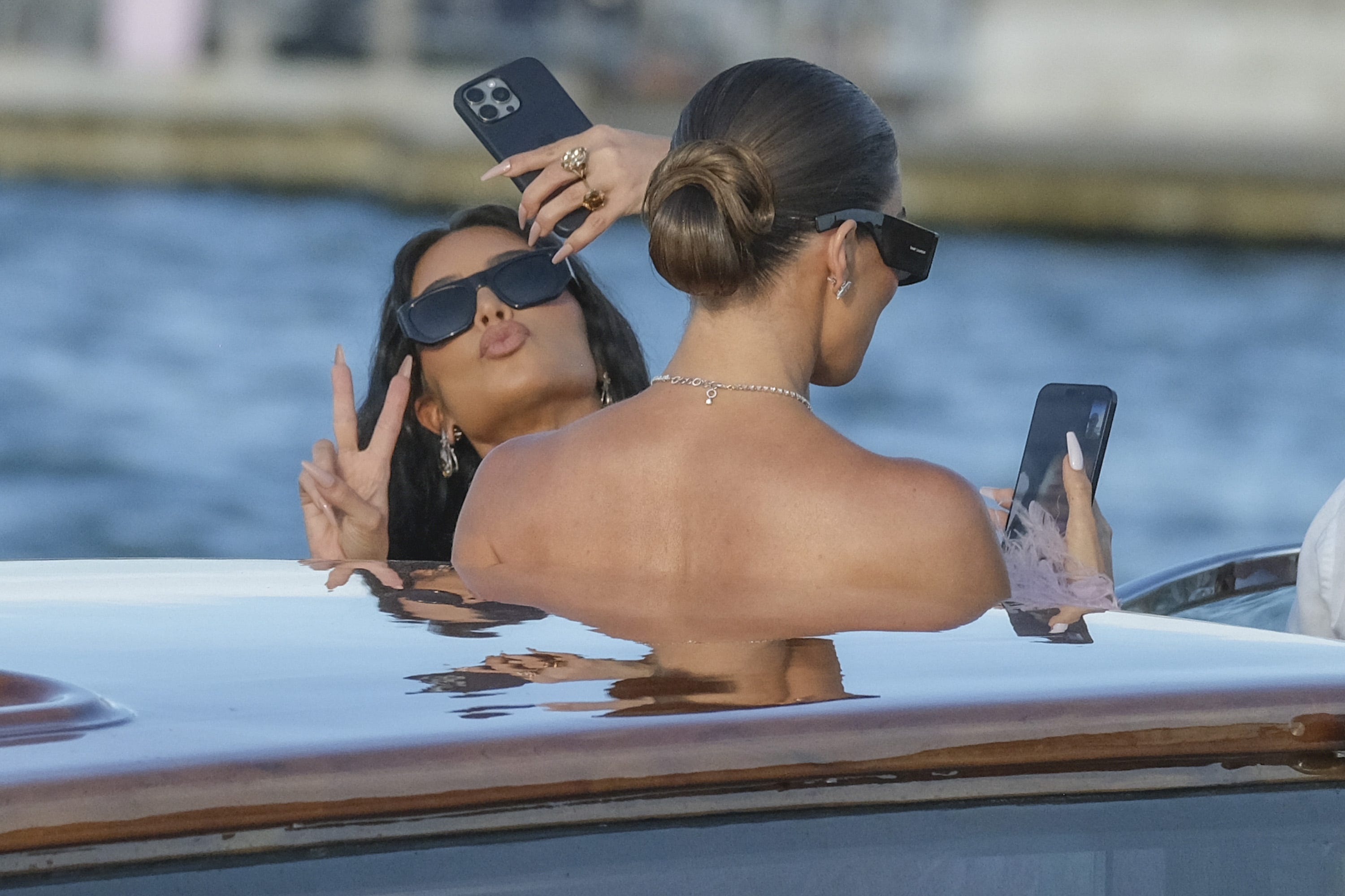 Kim Kardashian and Khloe Kardashian taking selfies on a boat.