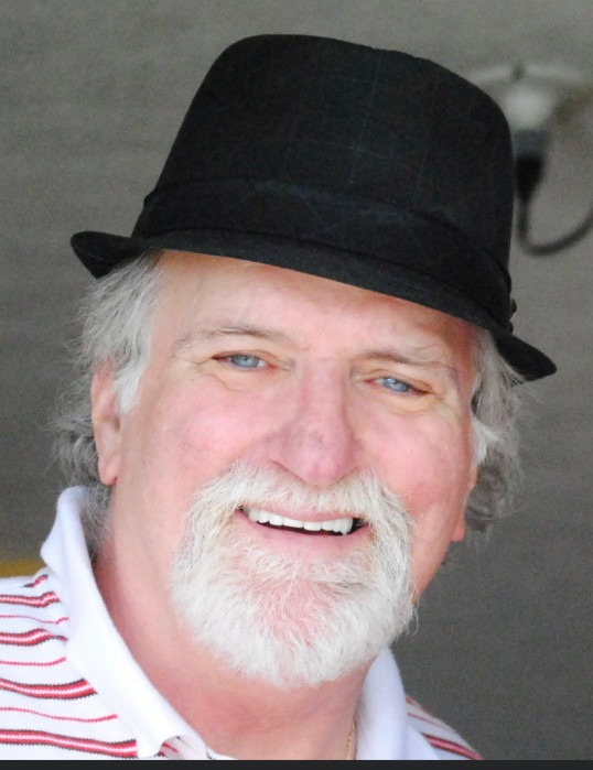 Portrait of a smiling man wearing a black fedora.