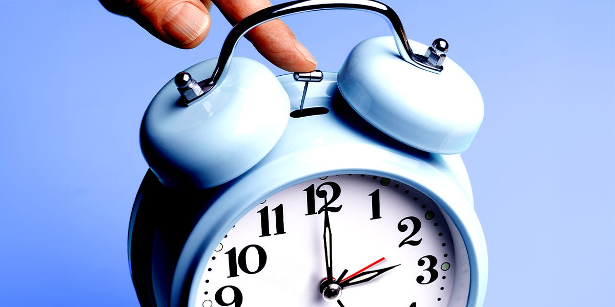 Hand stopping a blue alarm clock