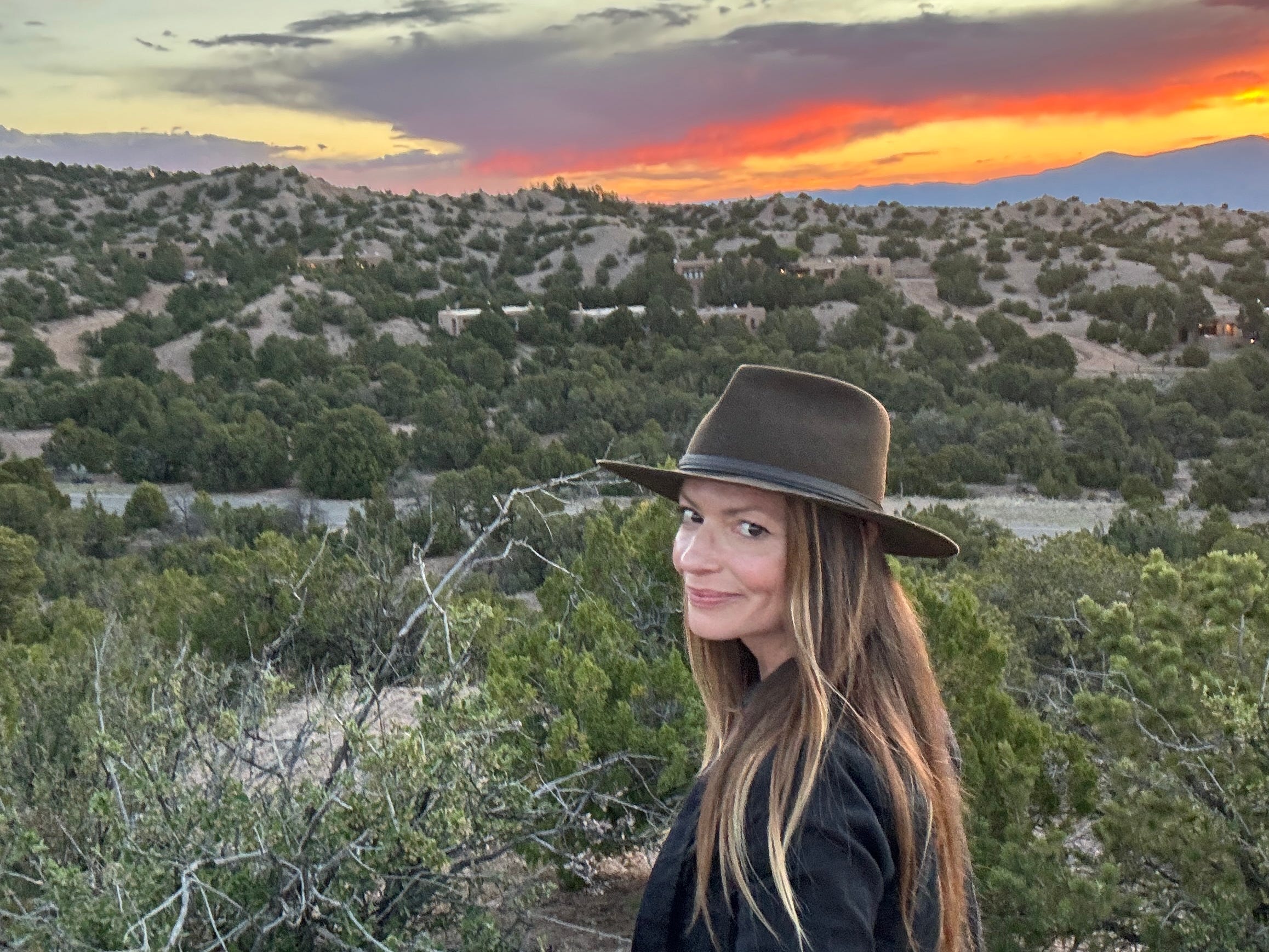 Emily taking a selfie in the desert in Santa Fe, with the sunset in the background.