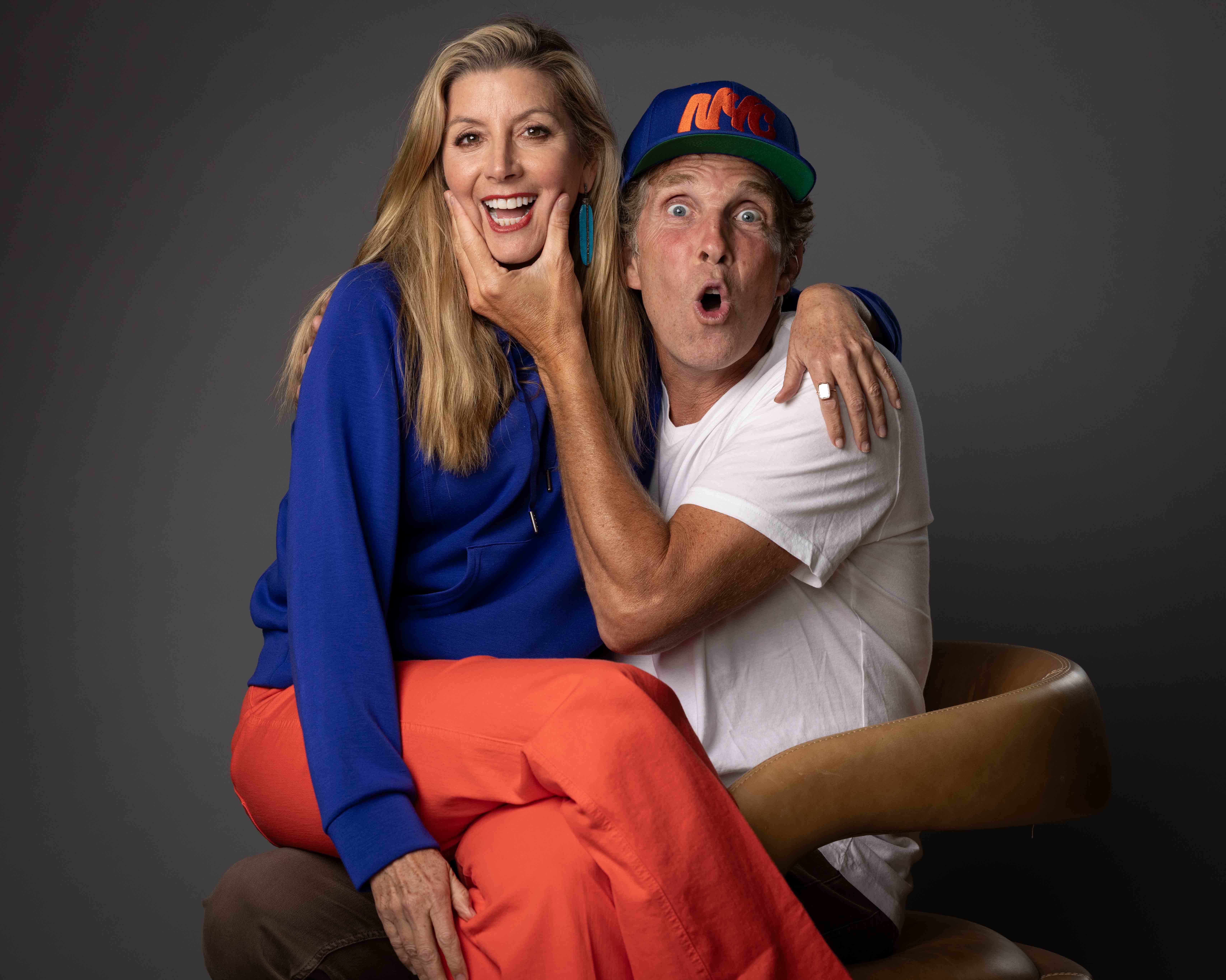 Jesse Itzler, with his wife, Sarah Blakely, sitting on his lap in a fun pose.