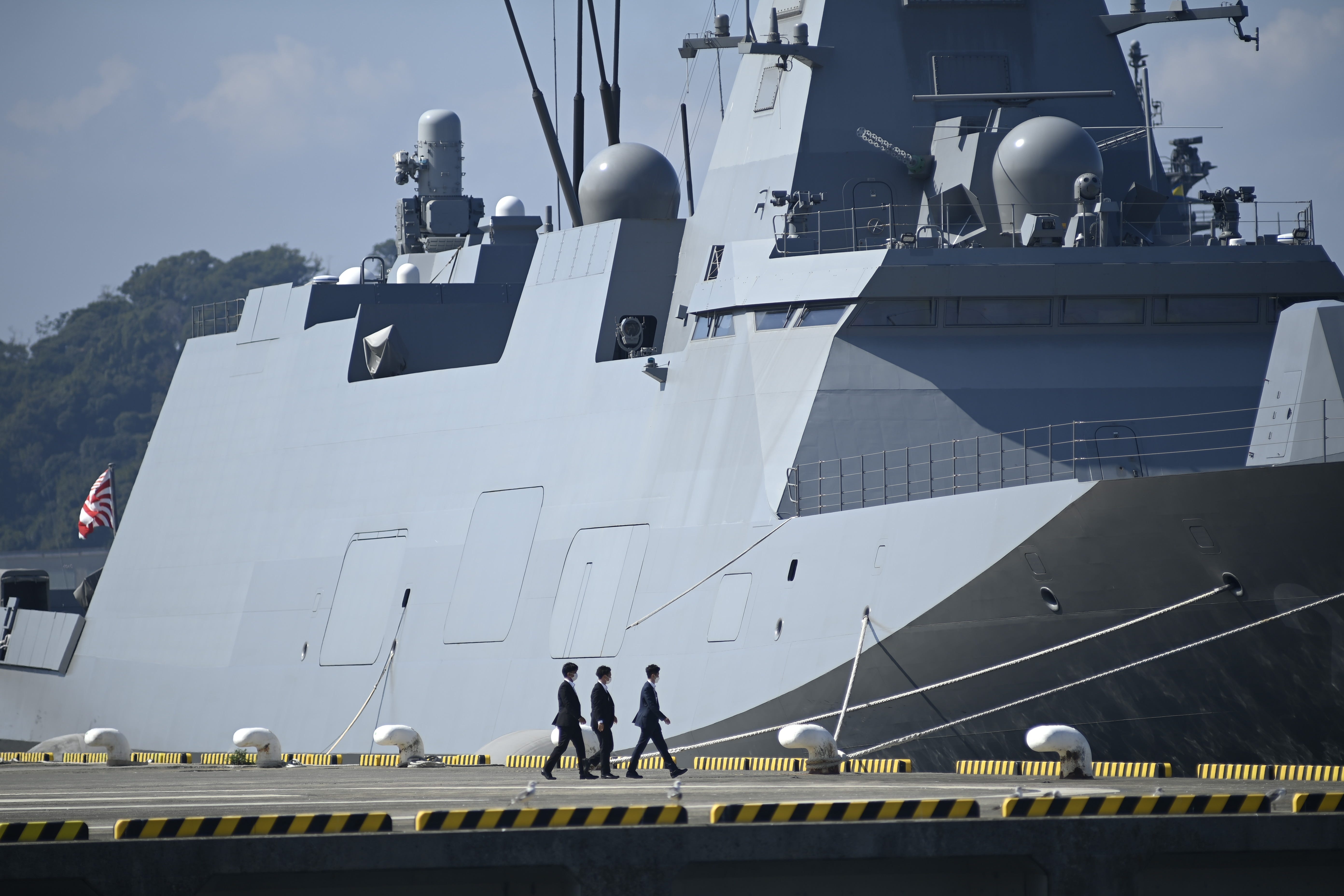 Security police patrol the docks near a Mogami-class frigate in Kanagawa.