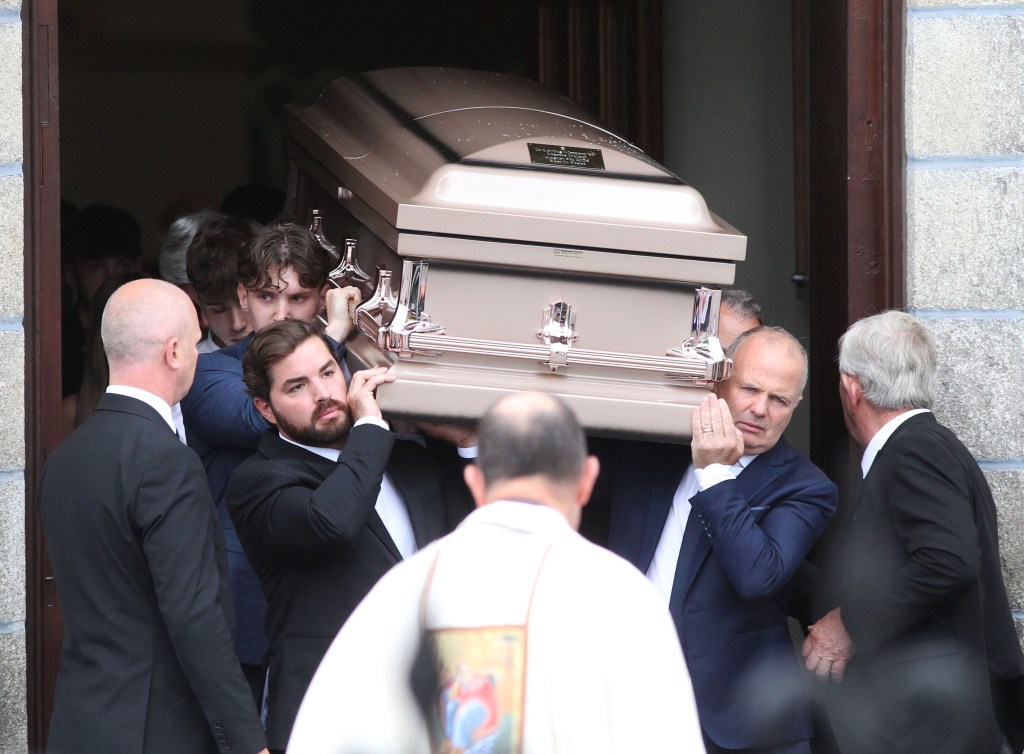 Pallbearers carrying a casket into a building.