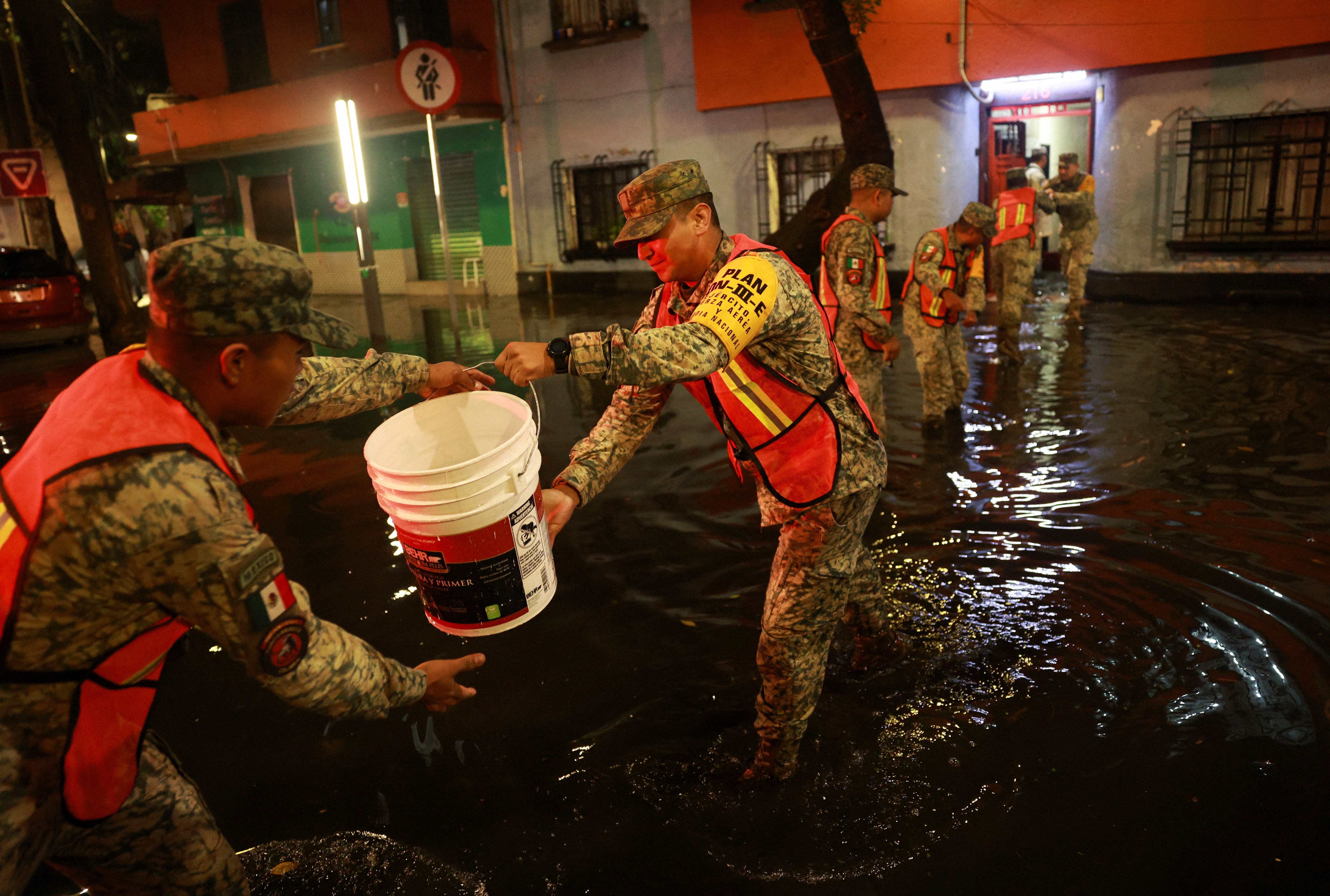 Soldiers remove water from a flooded house following heavy rainfall in Mexico City, Mexico, August 10, 2025.