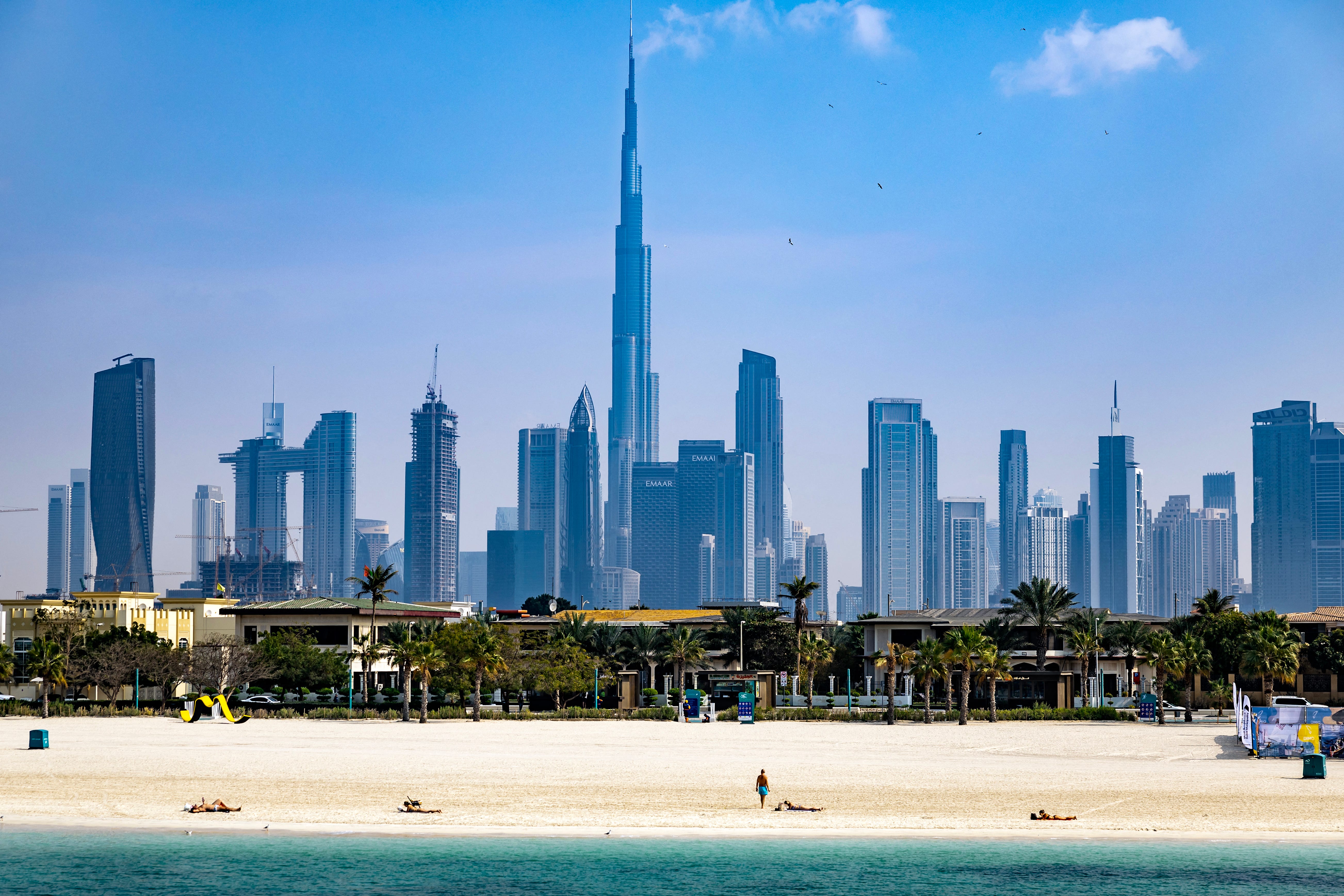 Burj Khalifa, the world's tallest building, adorns the Dubai skyline as people sunbathe on Jumerah Beach on January 30, 2025.