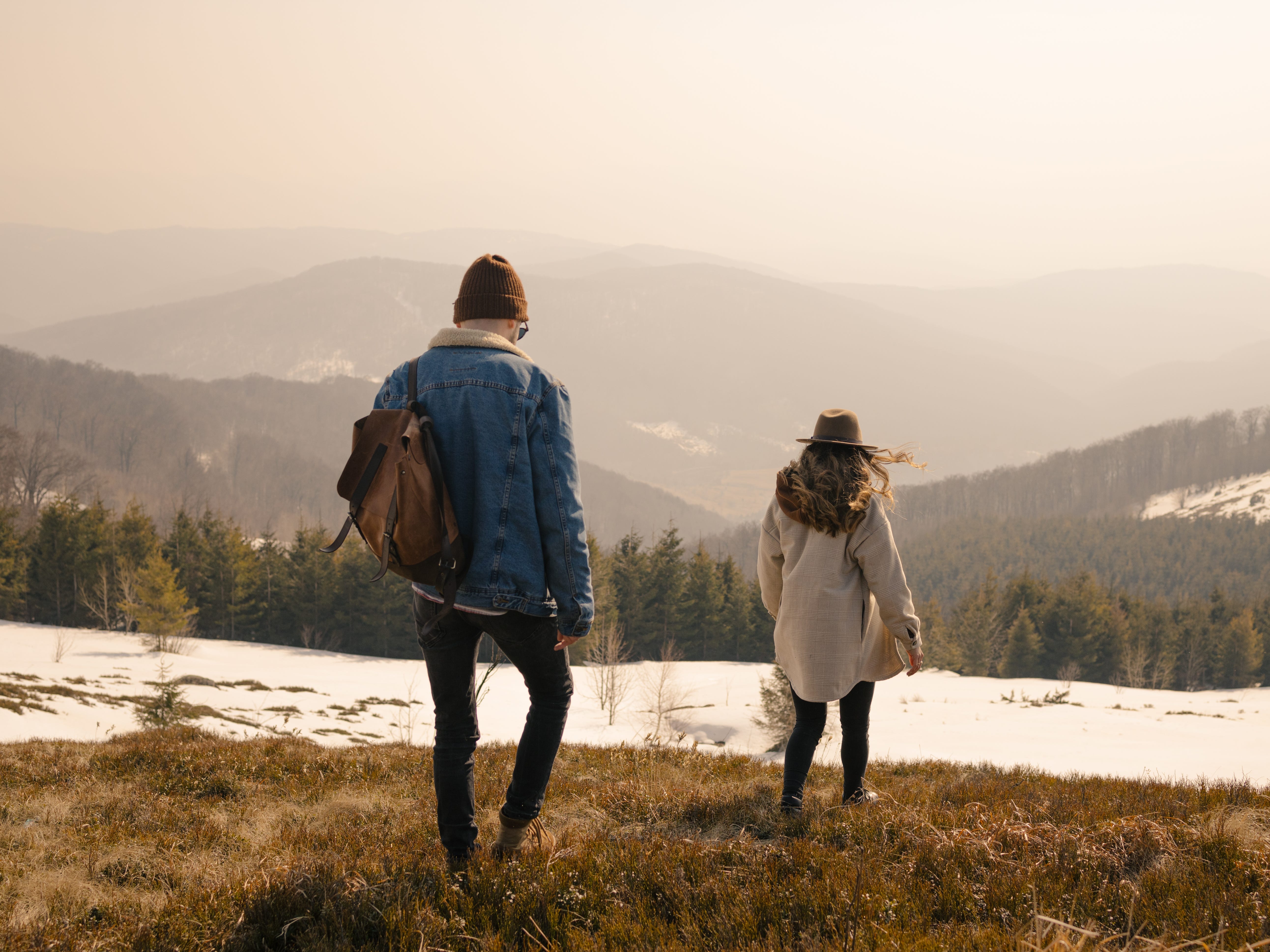A couple walking in a field toward a mountain.