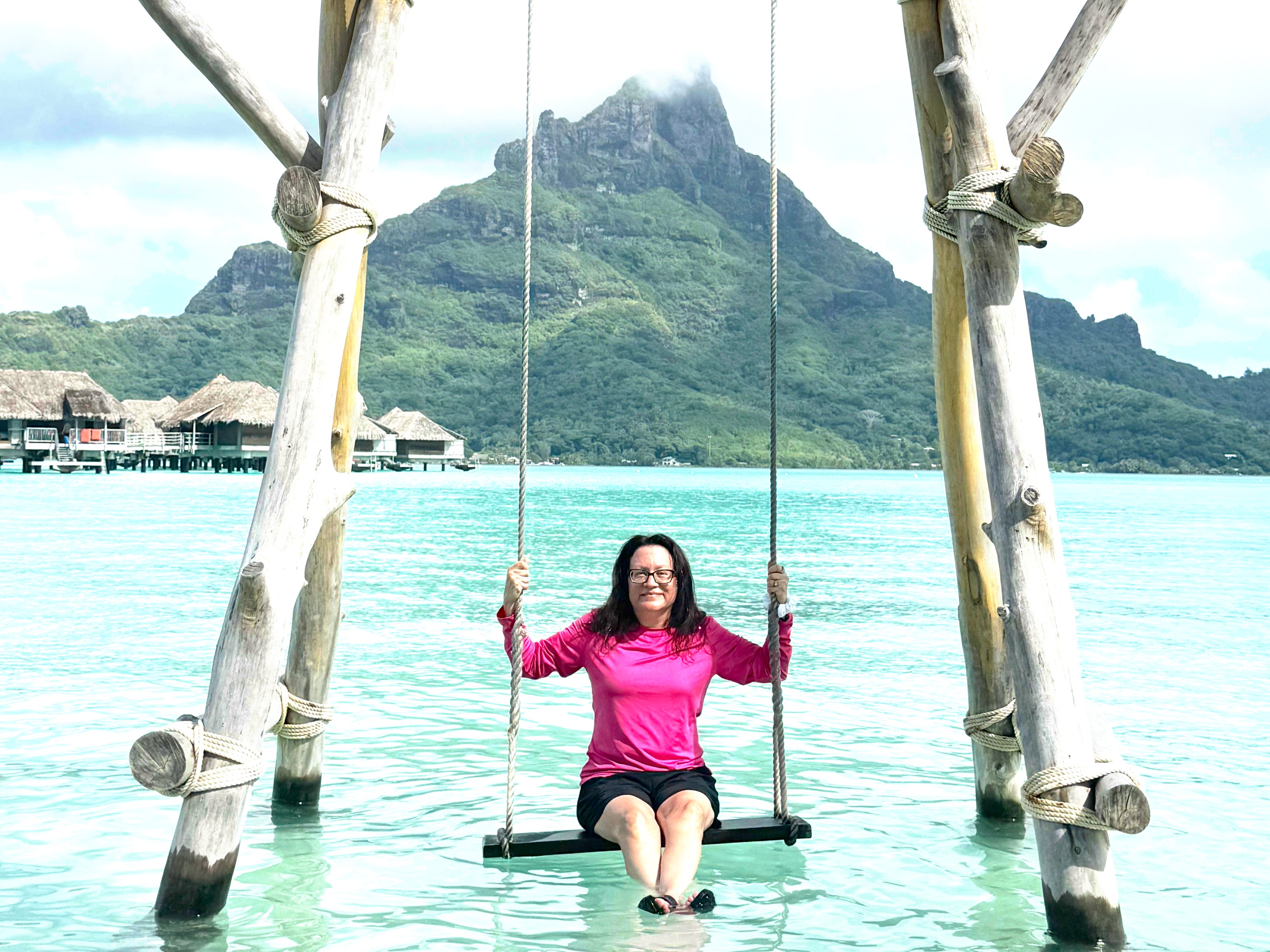 The author poses on a swing suspended over water in Bora Bora.