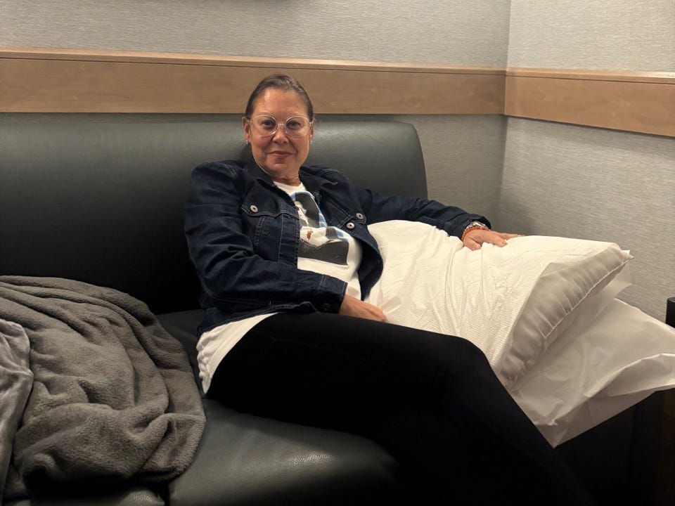 Author Jenny Powers sitting on daybed in nap room with pillows, blanket