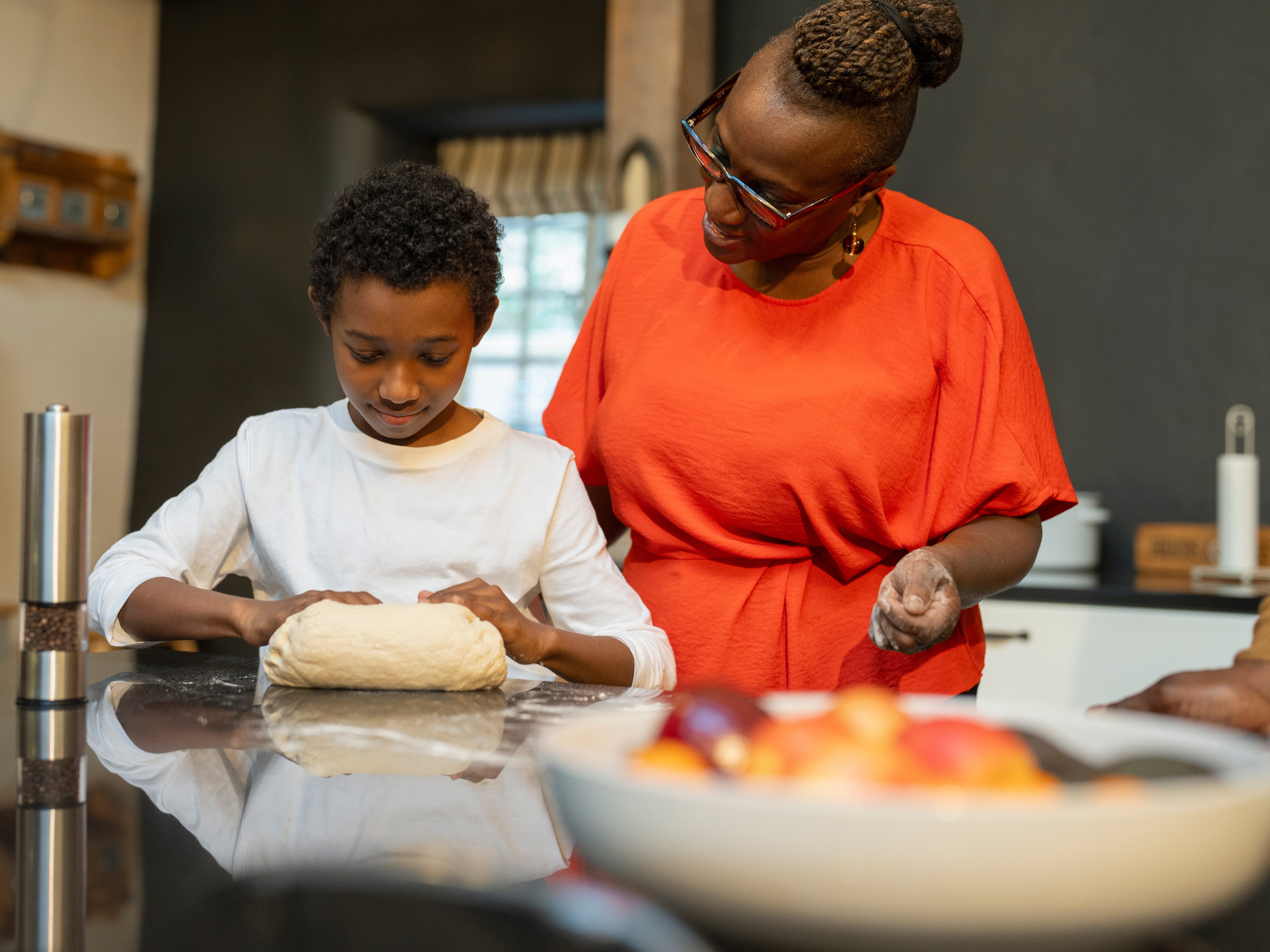 a grandmother watching her grandson knead dough
