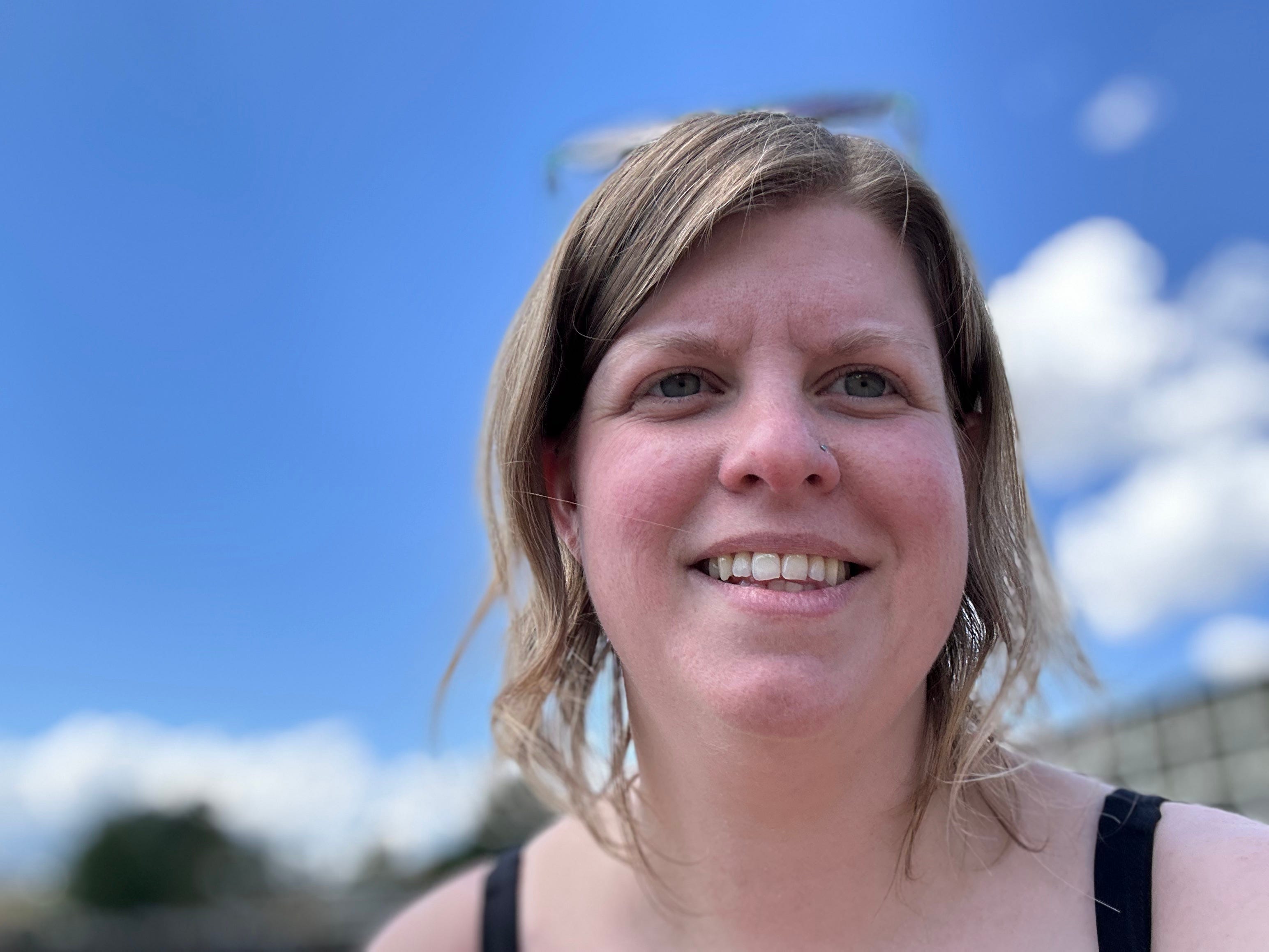 The author smiling while outside on a sunny day.