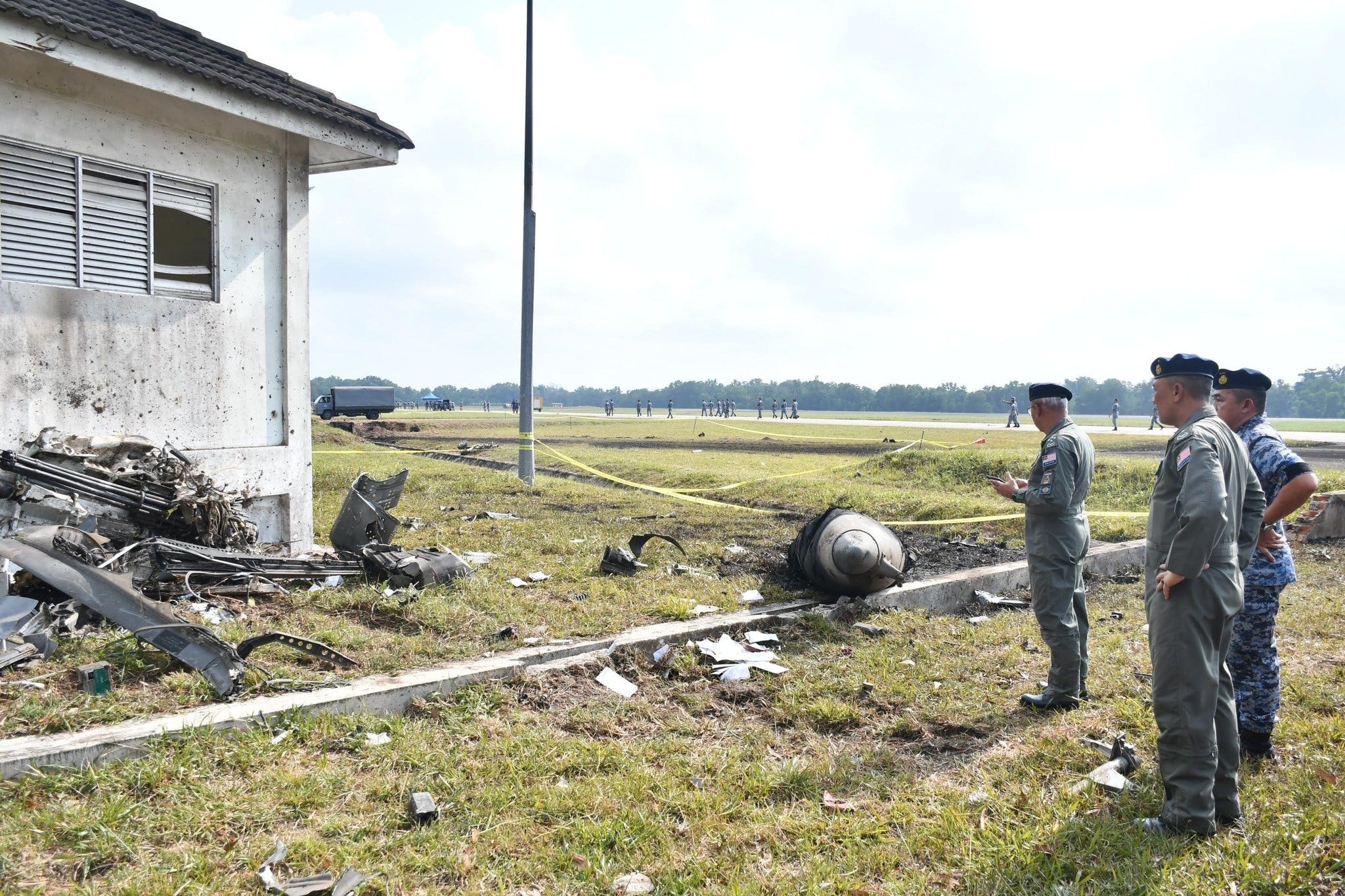 Malaysian officers observe the partial wreckage of an F/A-18.