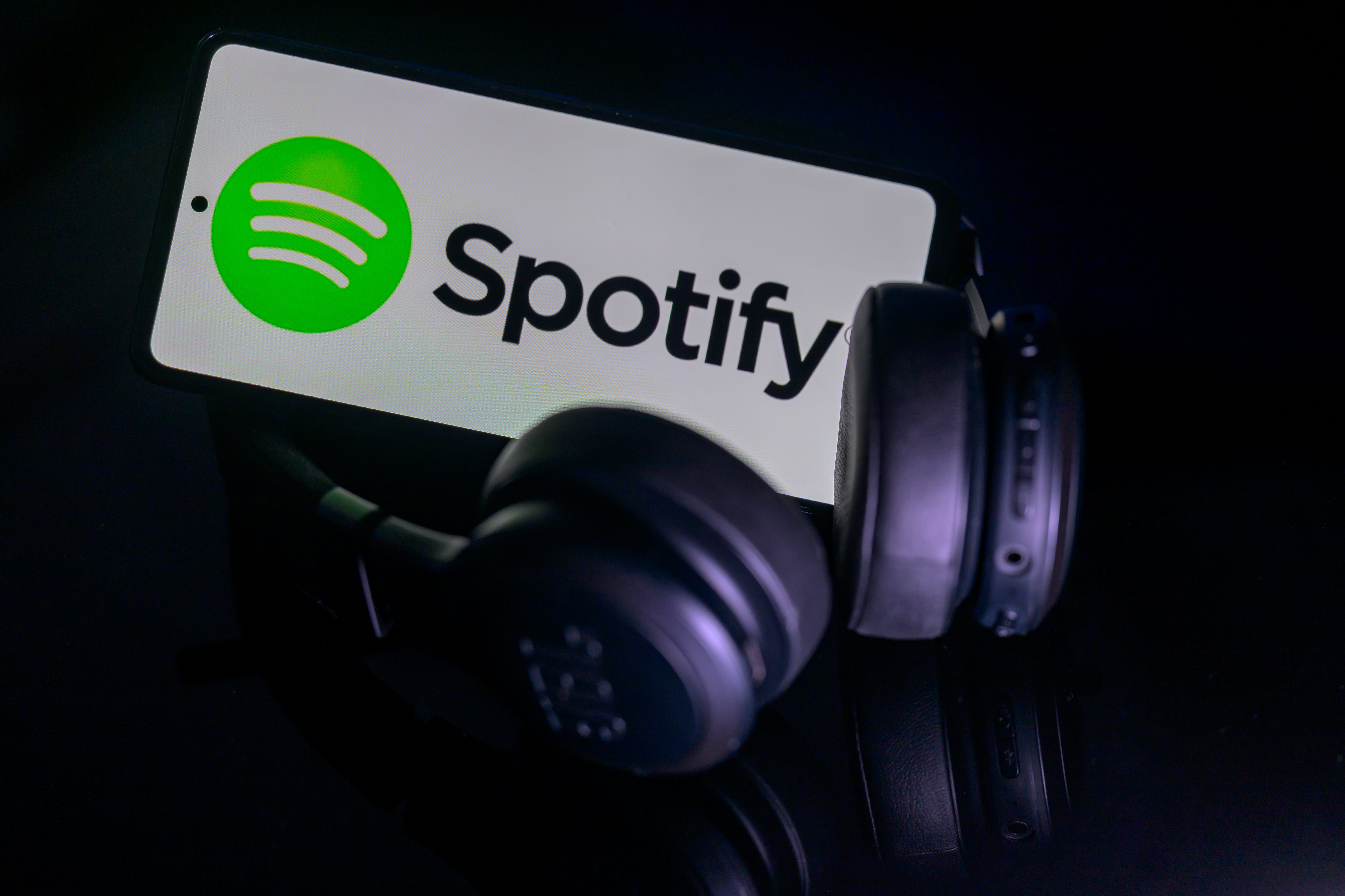 spotify logo on a phone next to headphones
