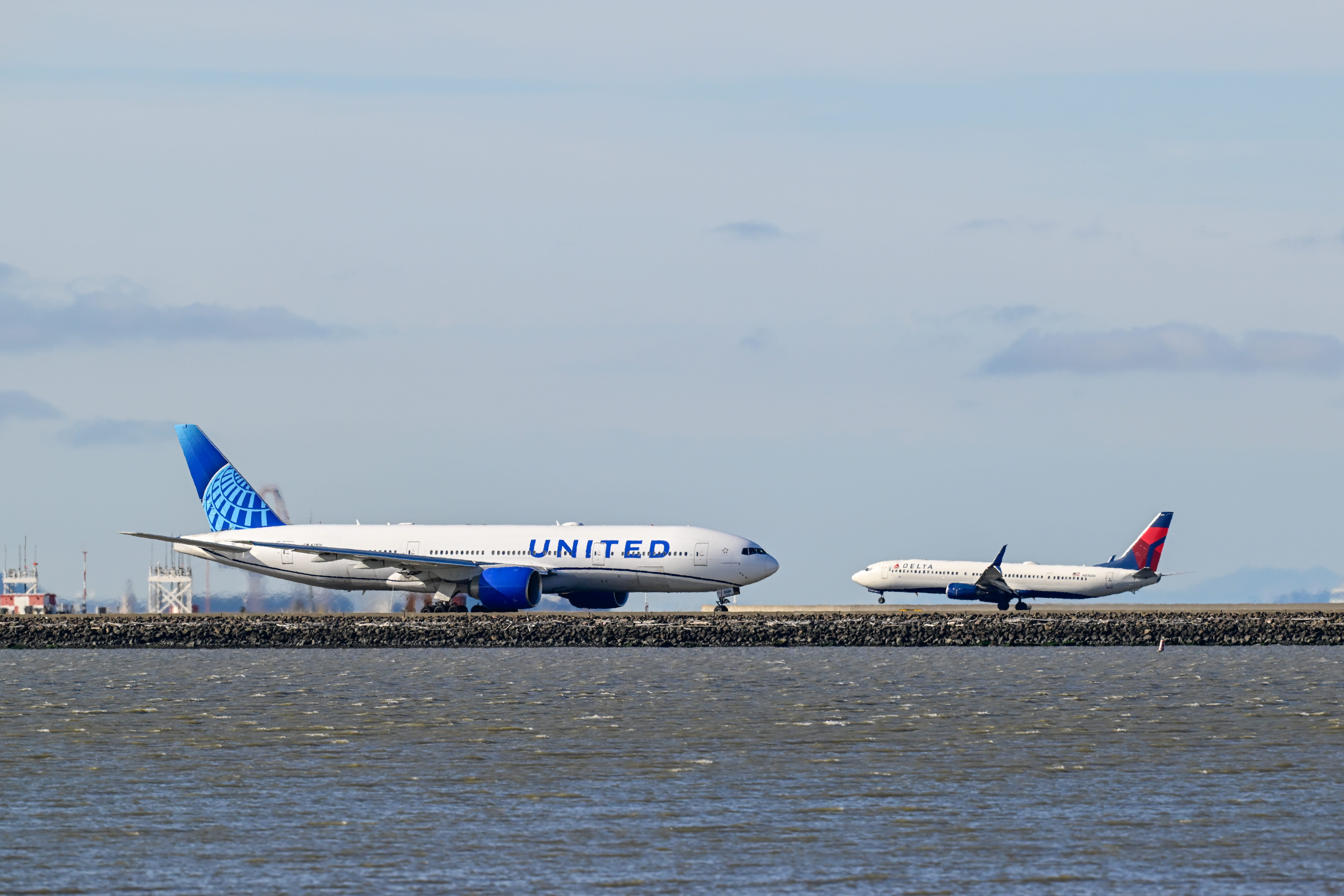 A Delta Airlines plane lands as a United Airlines plane is taxiing to takeoff at San Francisco International Airport (SFO) in San Francisco, California, United States on July 24, 2025.