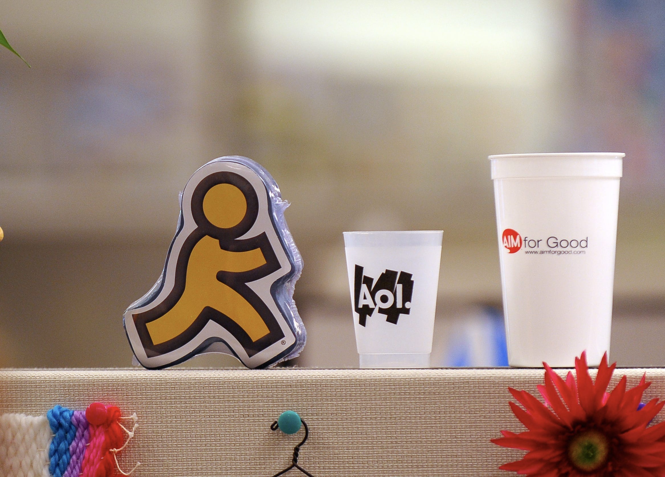 AOL running man logo on a shelf next to an AOL cup.