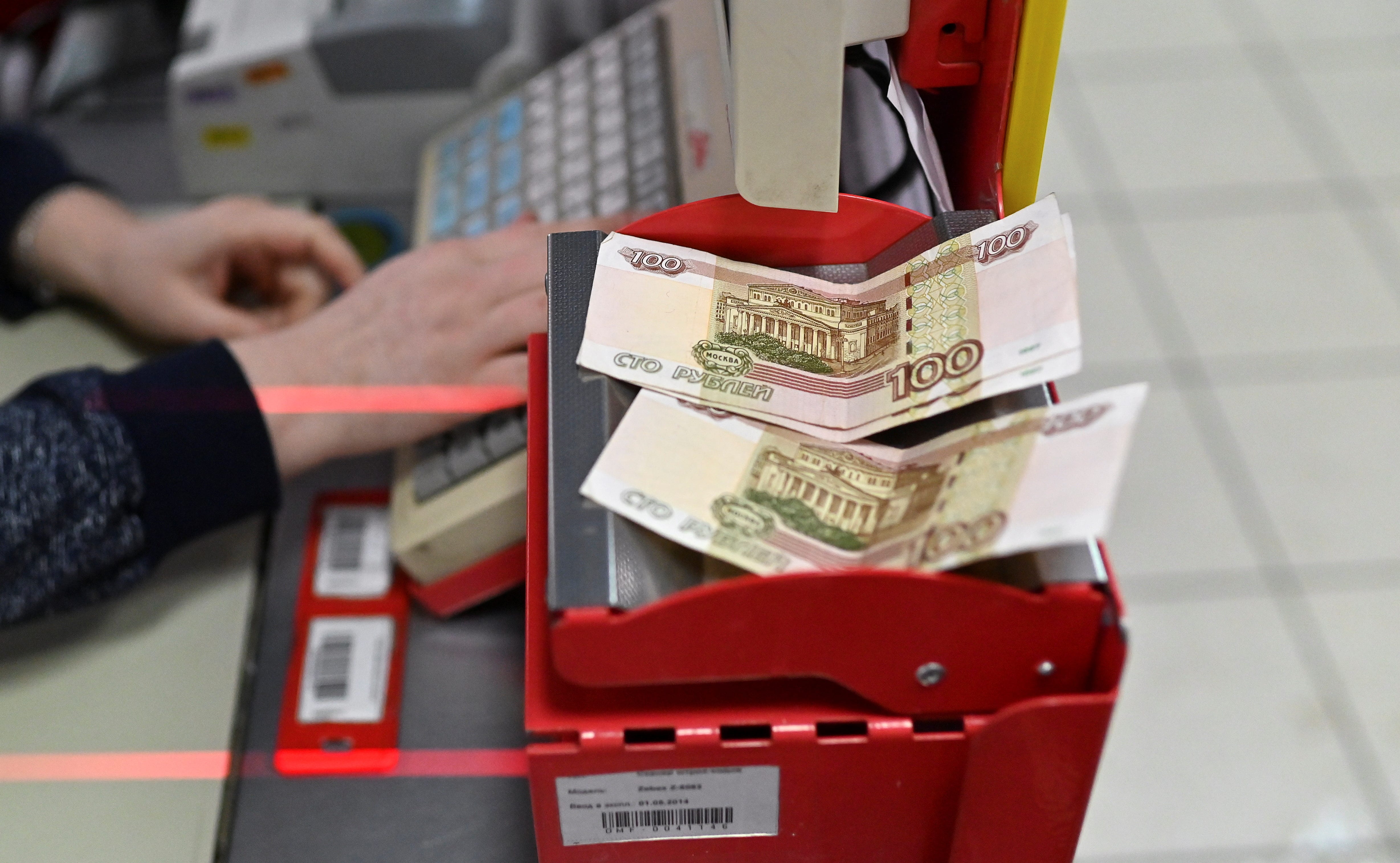 Russian 100-rouble banknotes are placed on a cashier's desk at a supermarket in Tara, Russia.