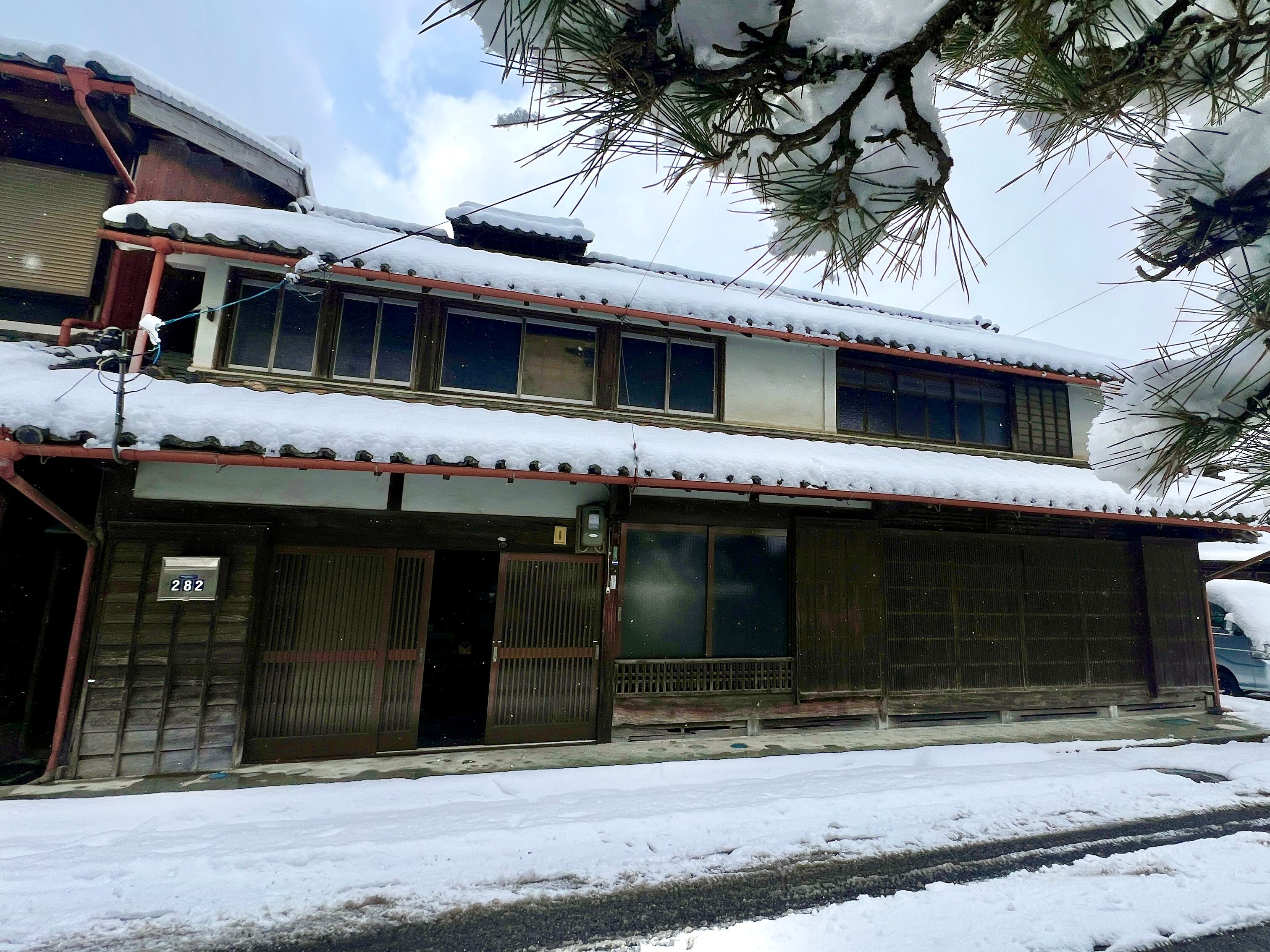 A traditional Japanese farmhouse covered in a blanket of snow during winter.
