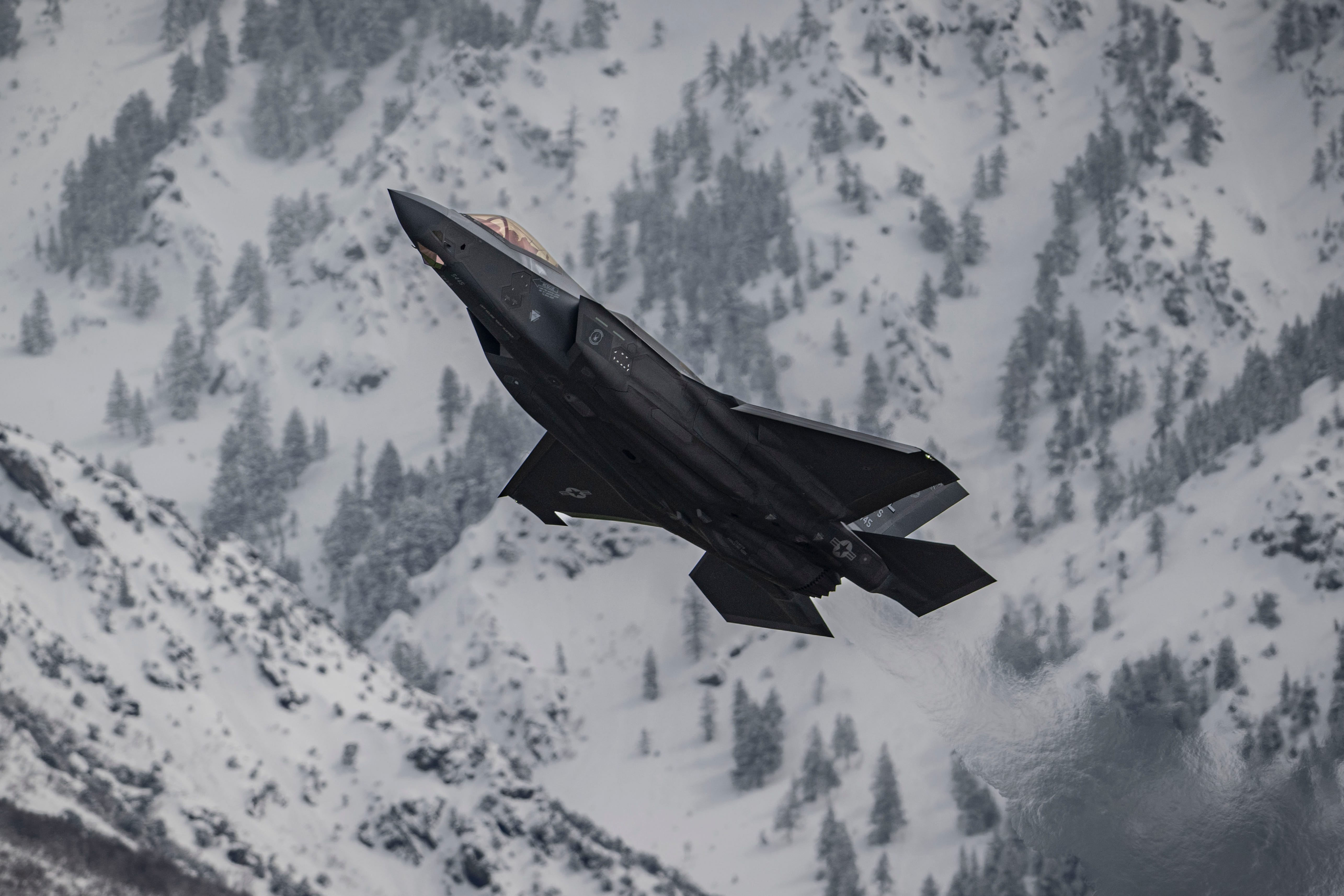 F-35 flying over snow-covered mountains.