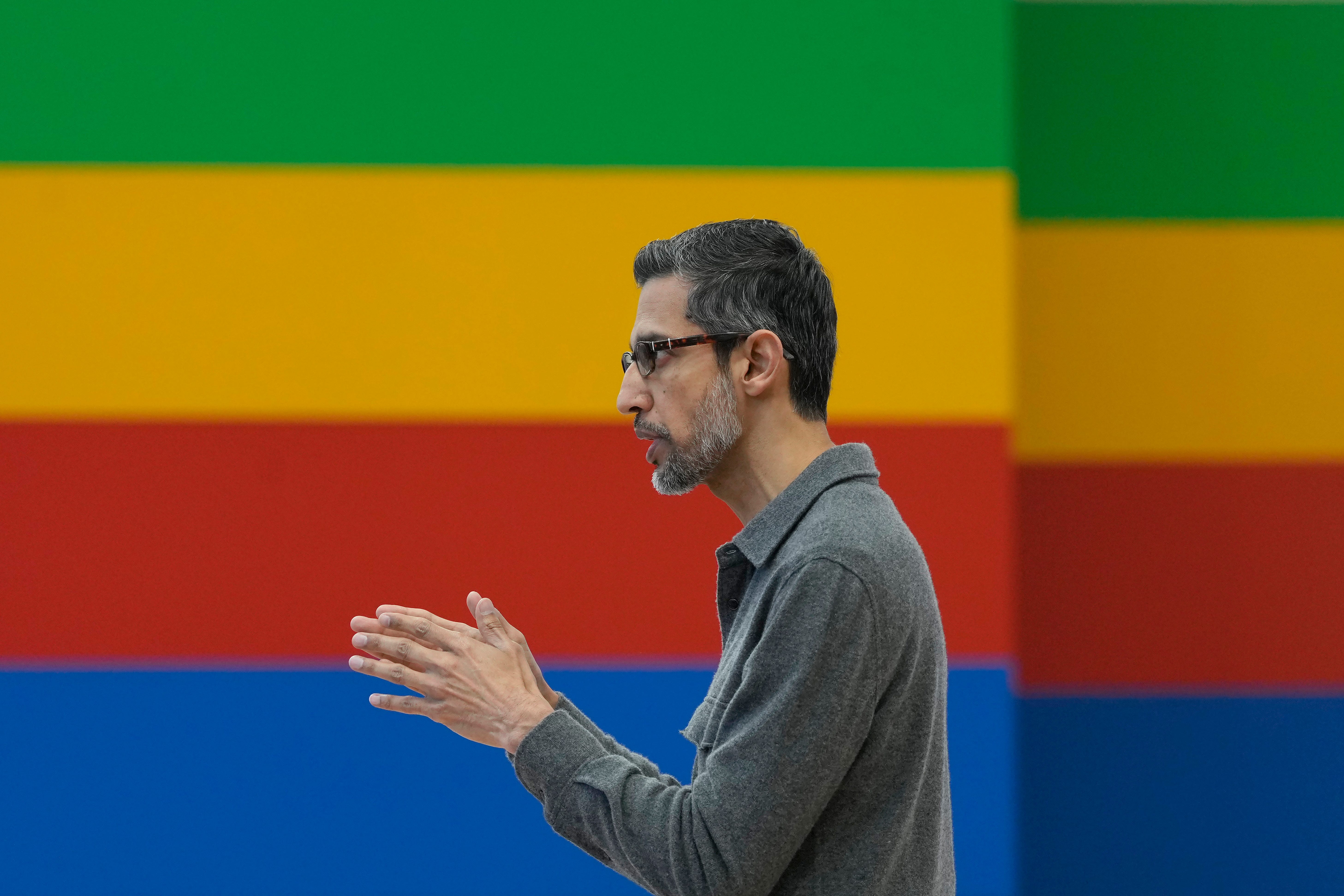 Sundar Pichai in front of a striped multicolored background.