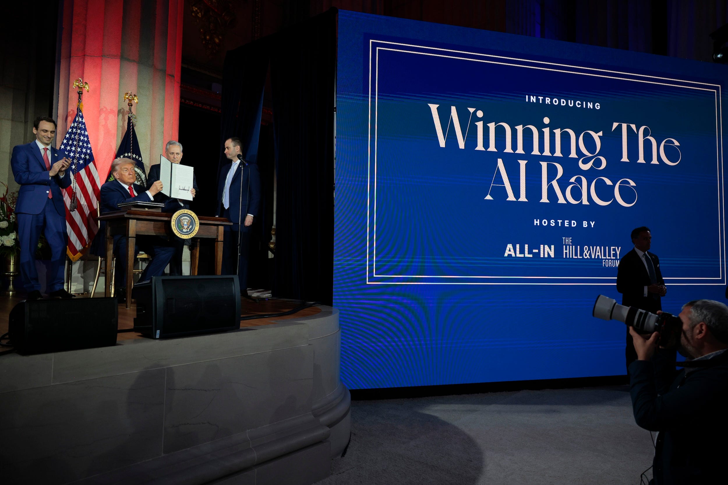 Donald Trump holds up an executive order during an announcement of his AI plan