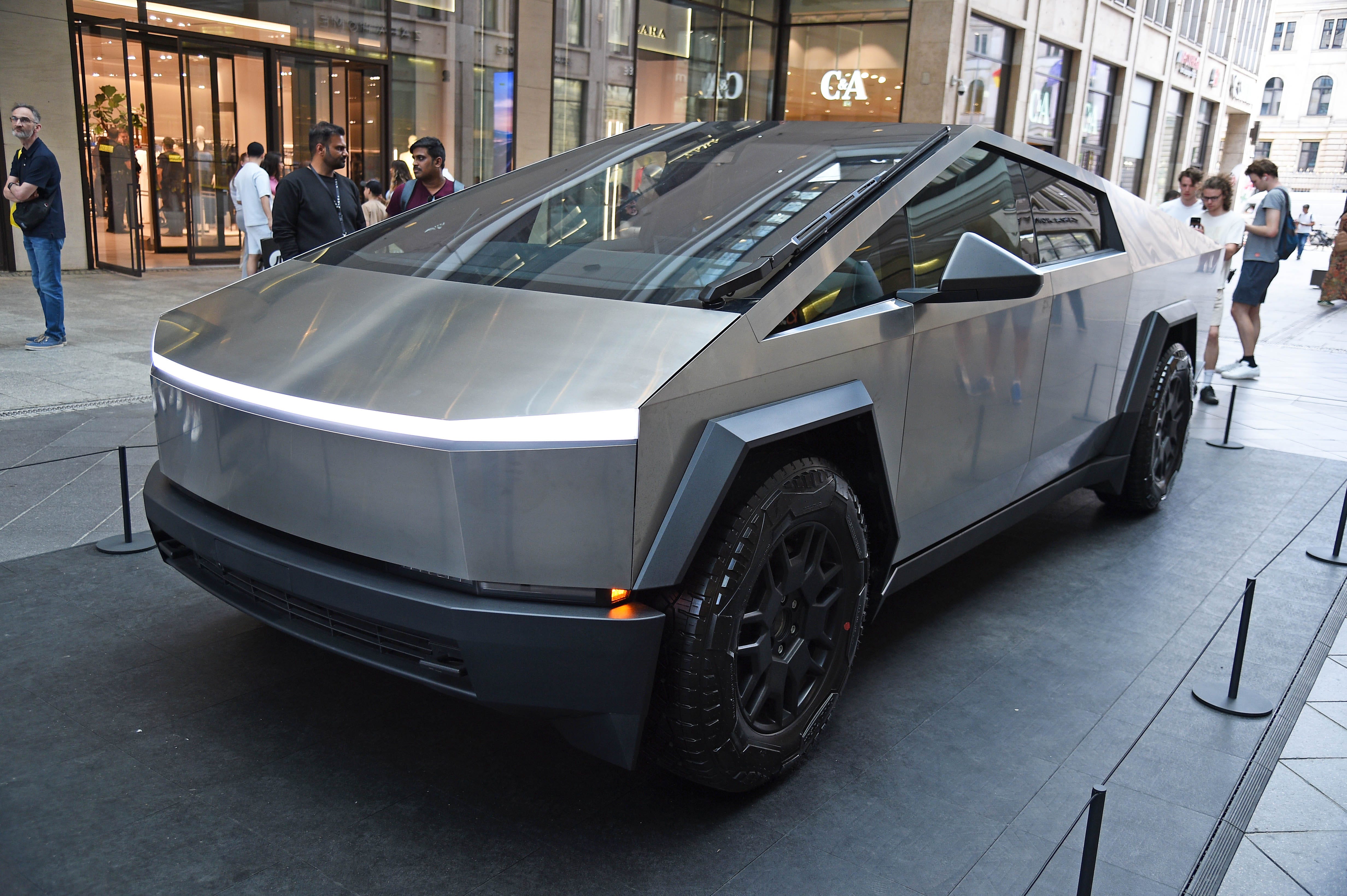 A Tesla Cybertruck on a street with people around it.