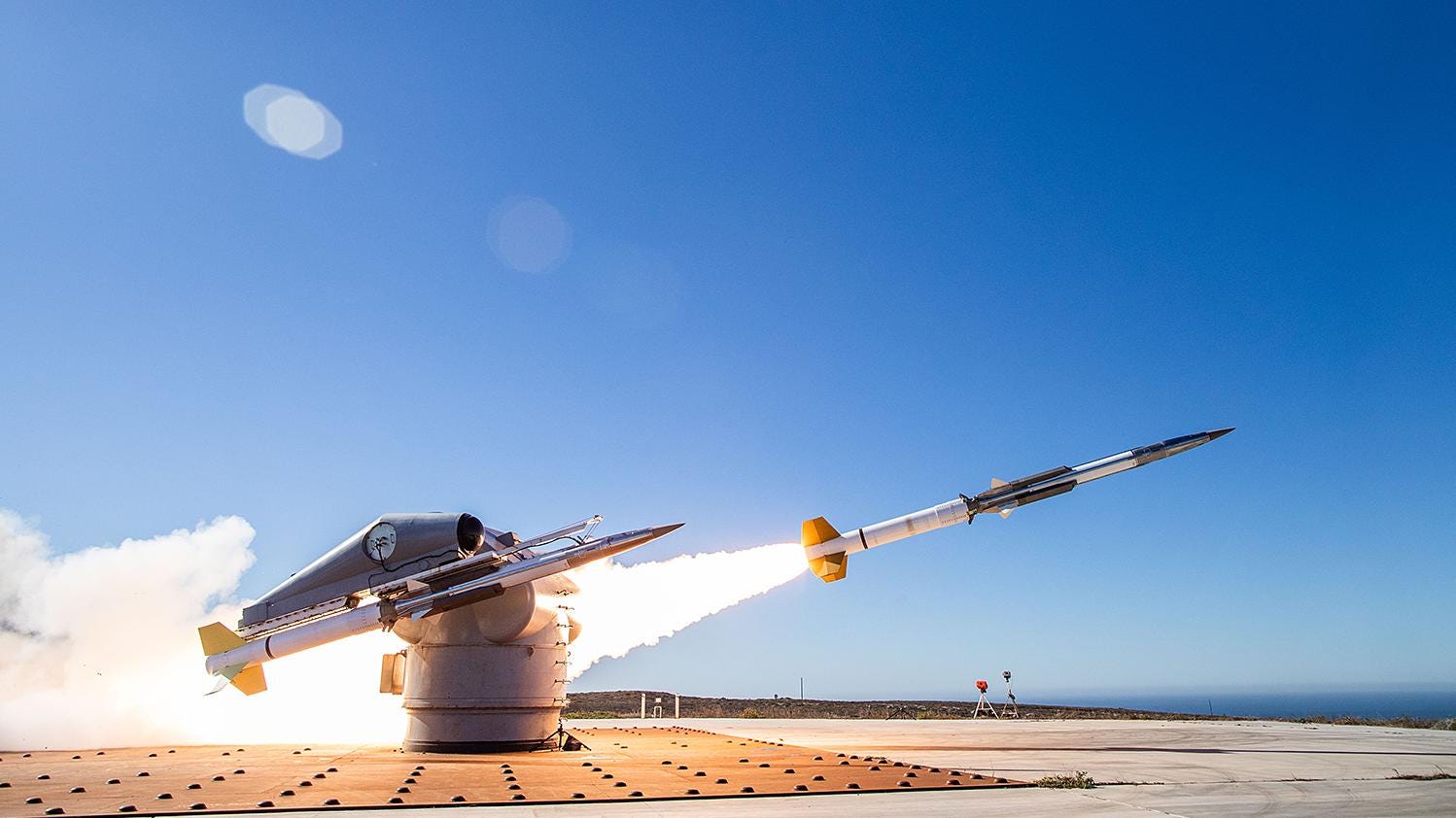 A GQM-163 target launches from San Nicolas Island. The sky is blue and clear in the background.
