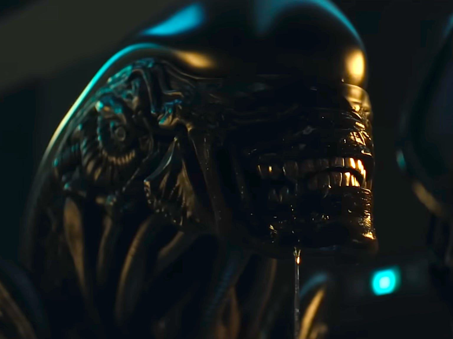 A black alien creature with a long domed head and thick muscles is in the center of the image. It has shiny silver teeth and there is a golden glow reflecting on its head.
