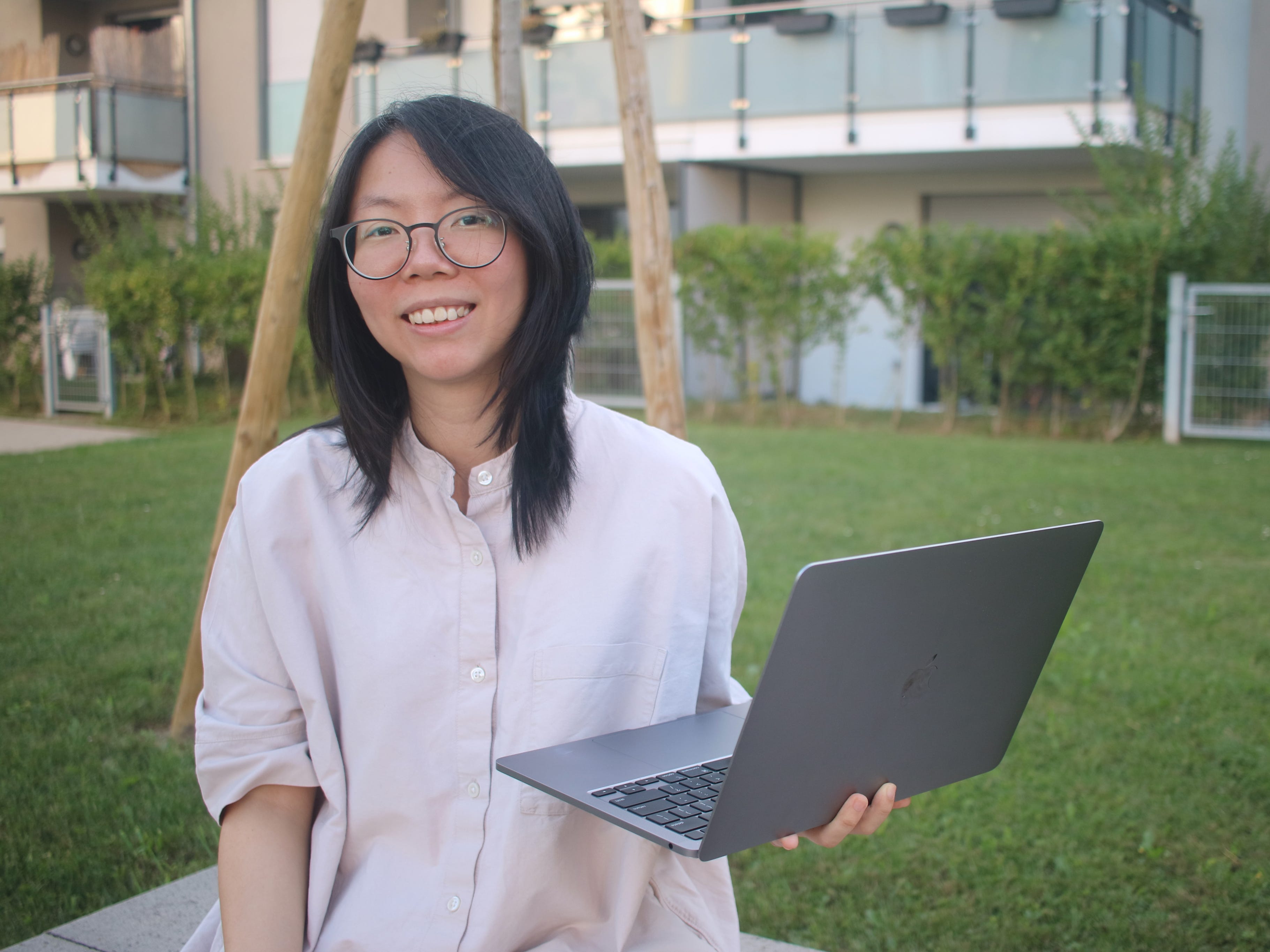 Melody Koh standing on grass and holding her laptop.
