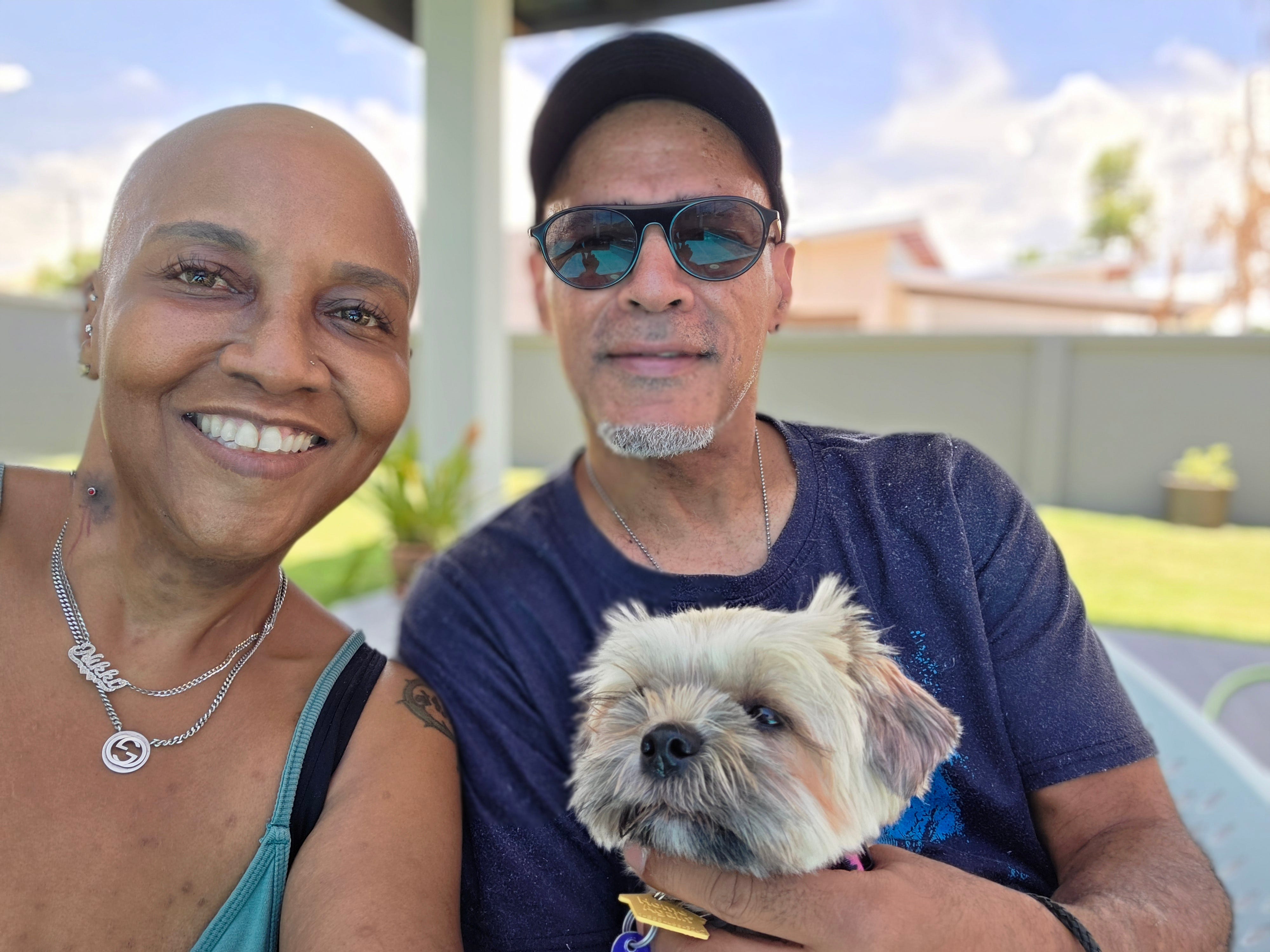 A couple posing for a photo with their dog.