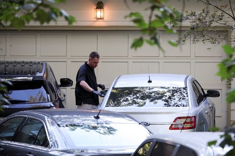 A man stands next to a car outside the home of the former White House national security adviser John Bolton as it is searched by FBI members, in Bethesda, MD on August 22, 2025.