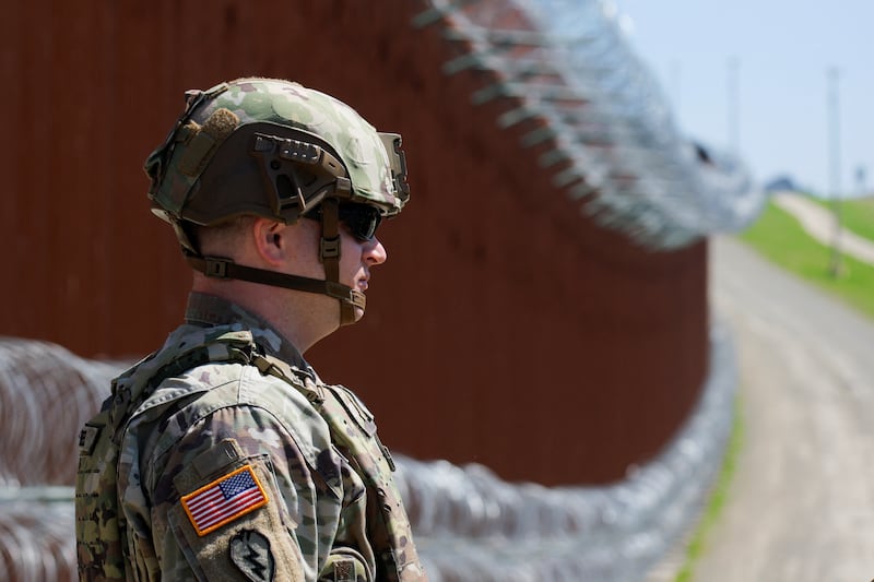 A member of the U.S. military stands guard on the southern border wall.