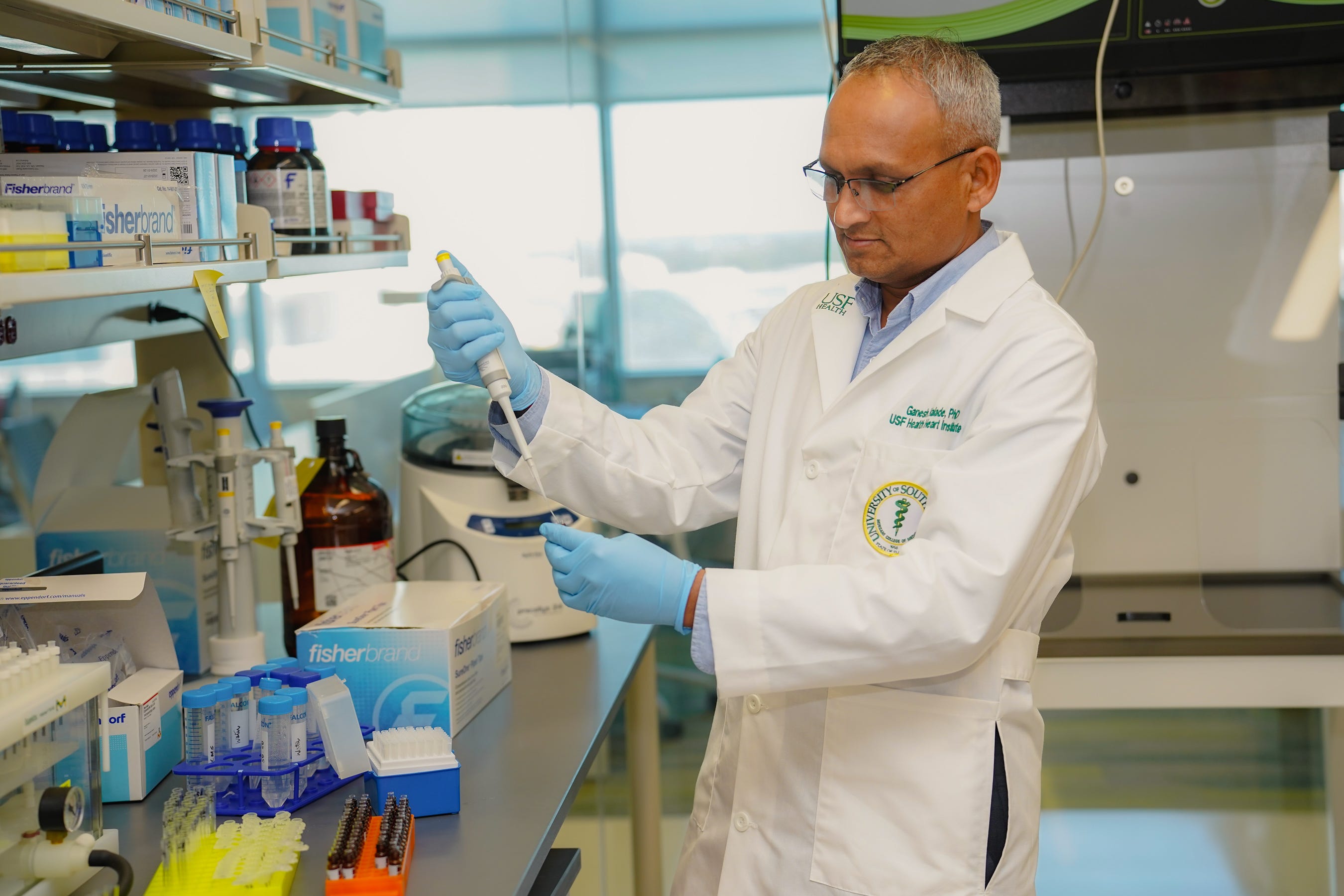 A man in a white coat in the lab working with science equipment that analyses lipids.
