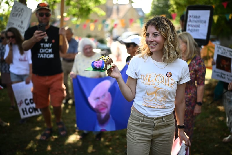 CHARLBURY, OXFORDSHIRE - AUGUST 12: A protestor holds a cake with a satirical image of US Vice-President JD Vance attached during a 