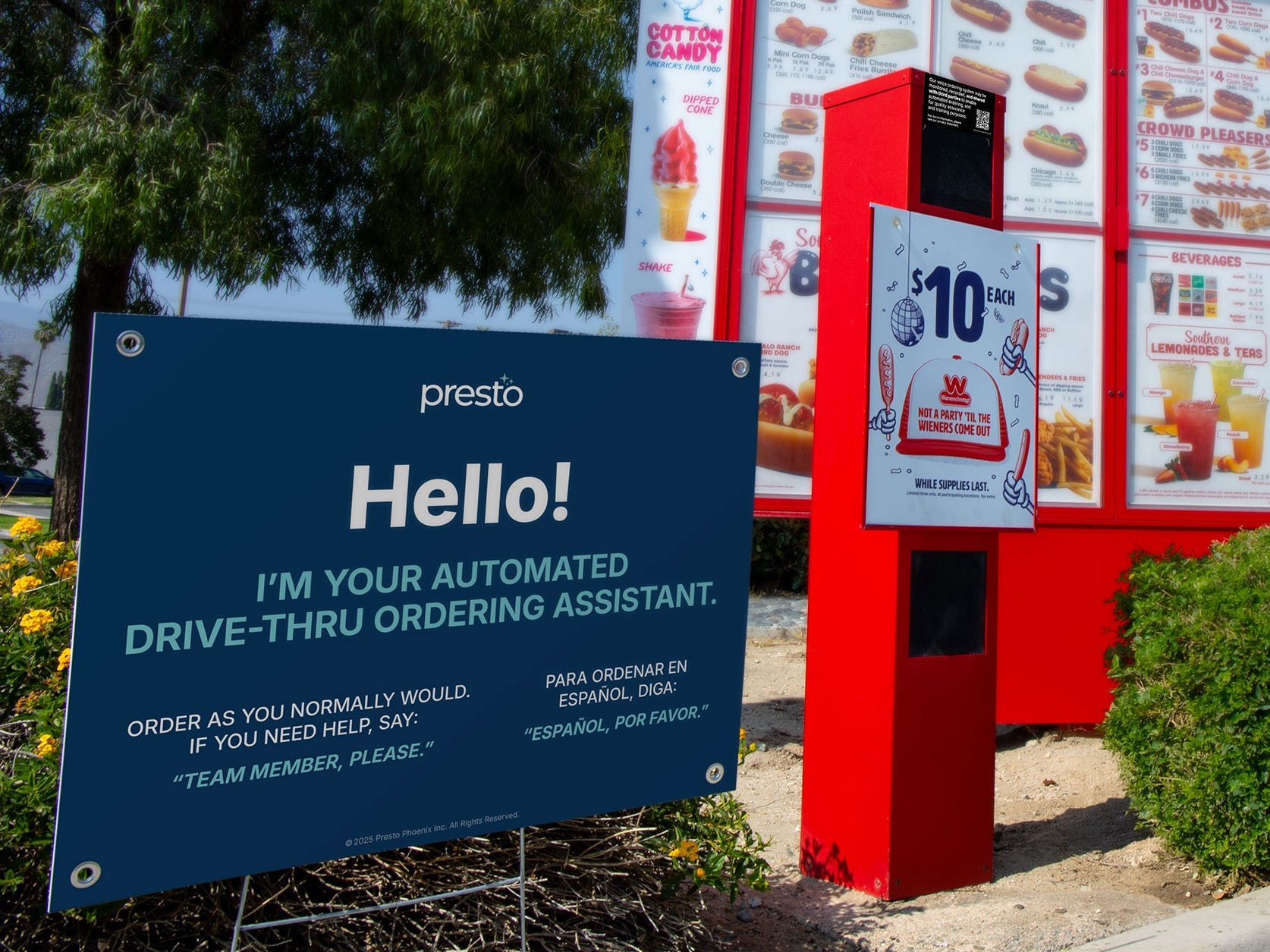 A sign outside a Wienerschnitzel drive-thru indicates an AI-powered ordering assistant will be taking customers' orders.