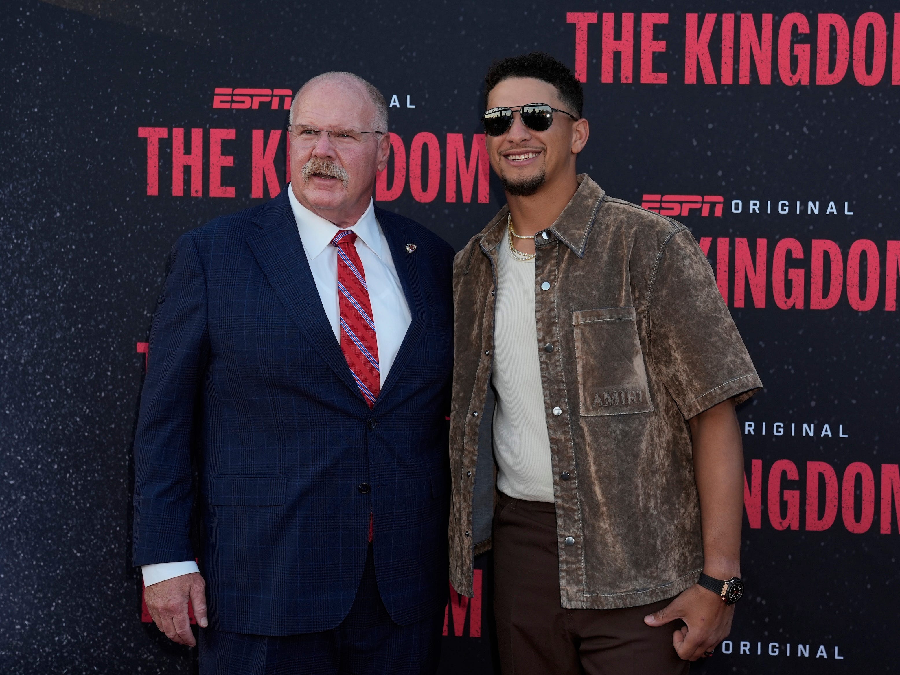 Andy Reid and Patrick Mahomes pose for photos together on "The Kingdom" red carpet in Kansas City, Missouri.