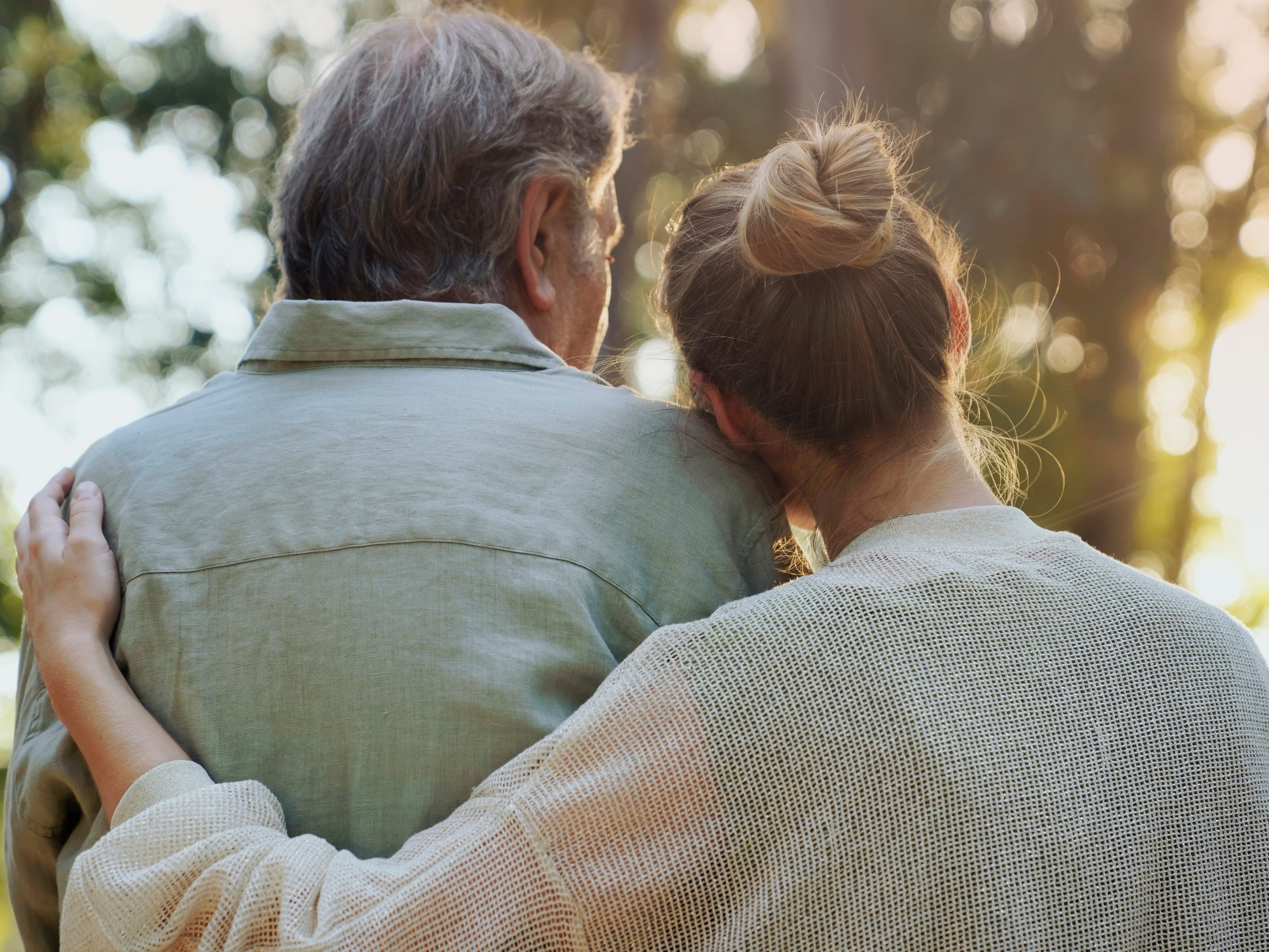 A woman hugging an older man in a park.