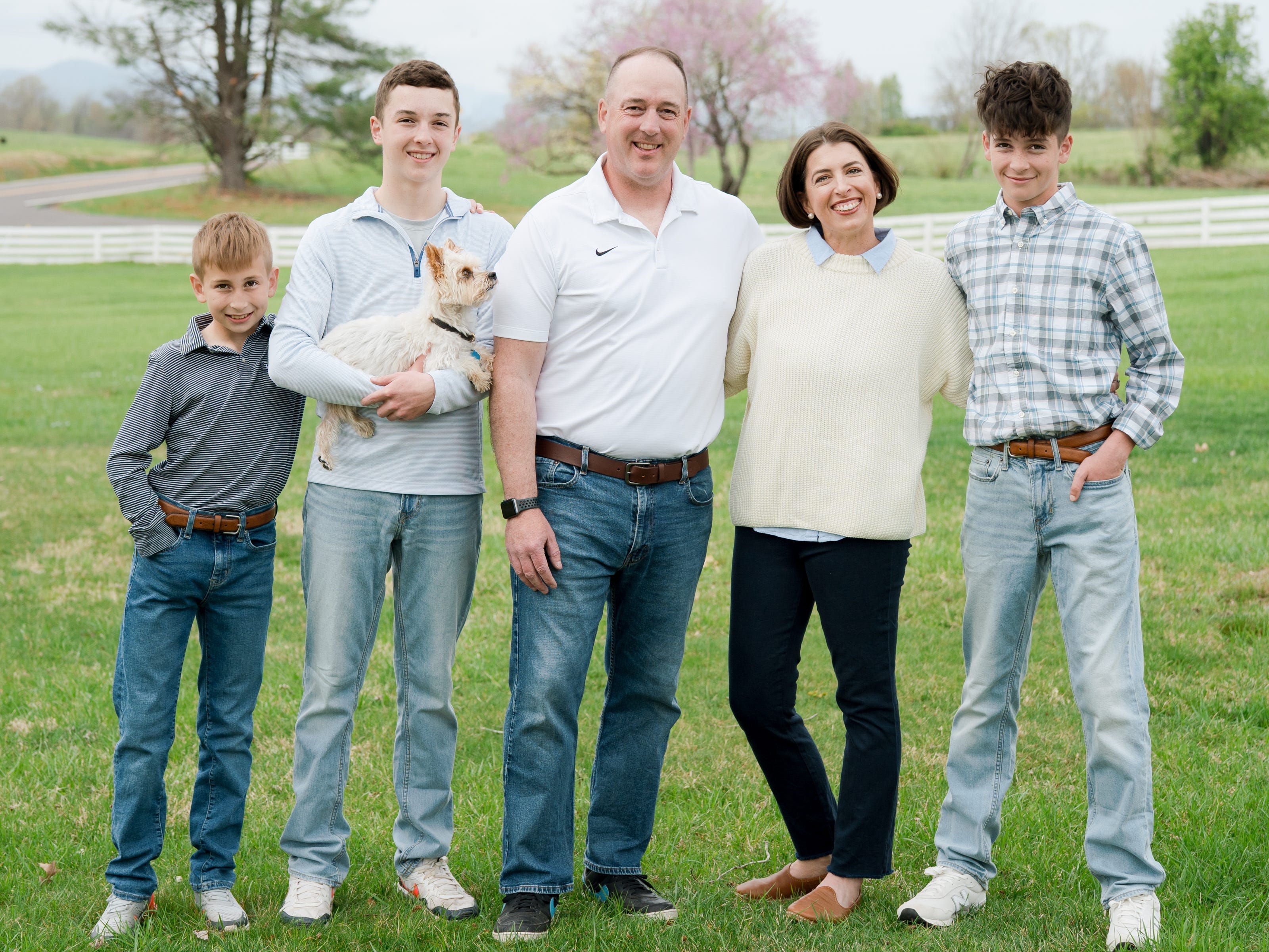 Blair Lonergan and her family, standing outside in a field, smiling at the camera with their family dog.