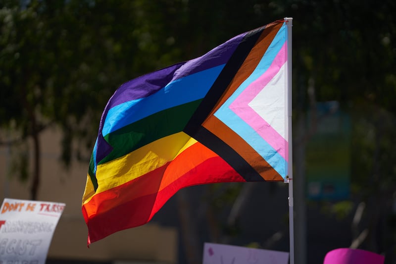 A Progress Pride Flag is held above the crowd of LGBTQ+ activists during the Los Angeles LGBT Center's 