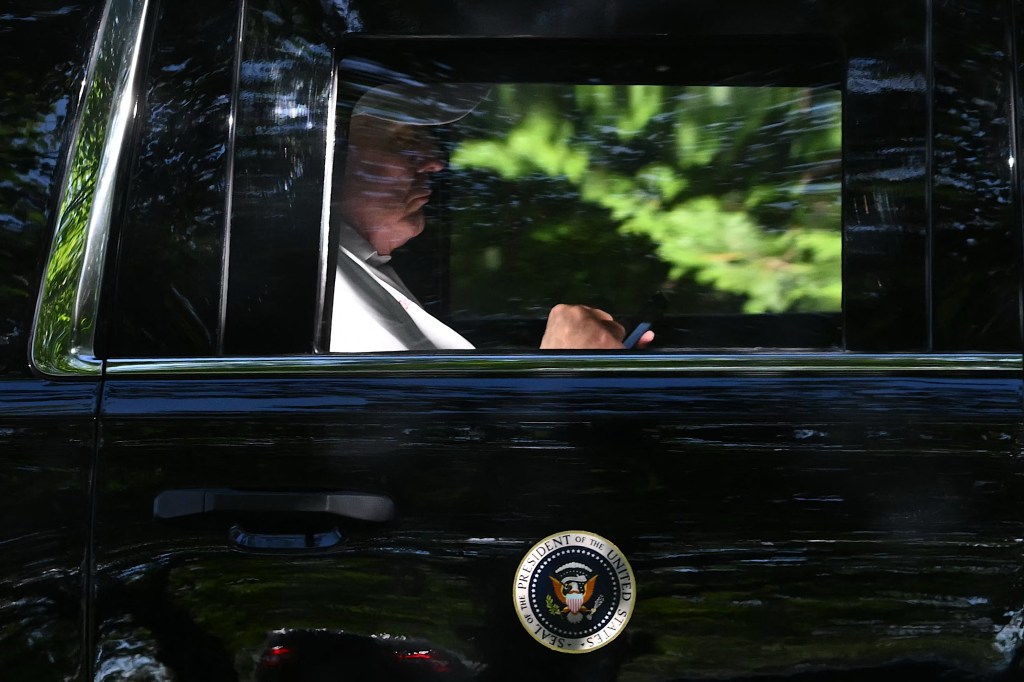 President Donald Trump checks his phone as he departs from Trump National golf course in Sterling, Virginia on August 31, 2025, en route to the White House.