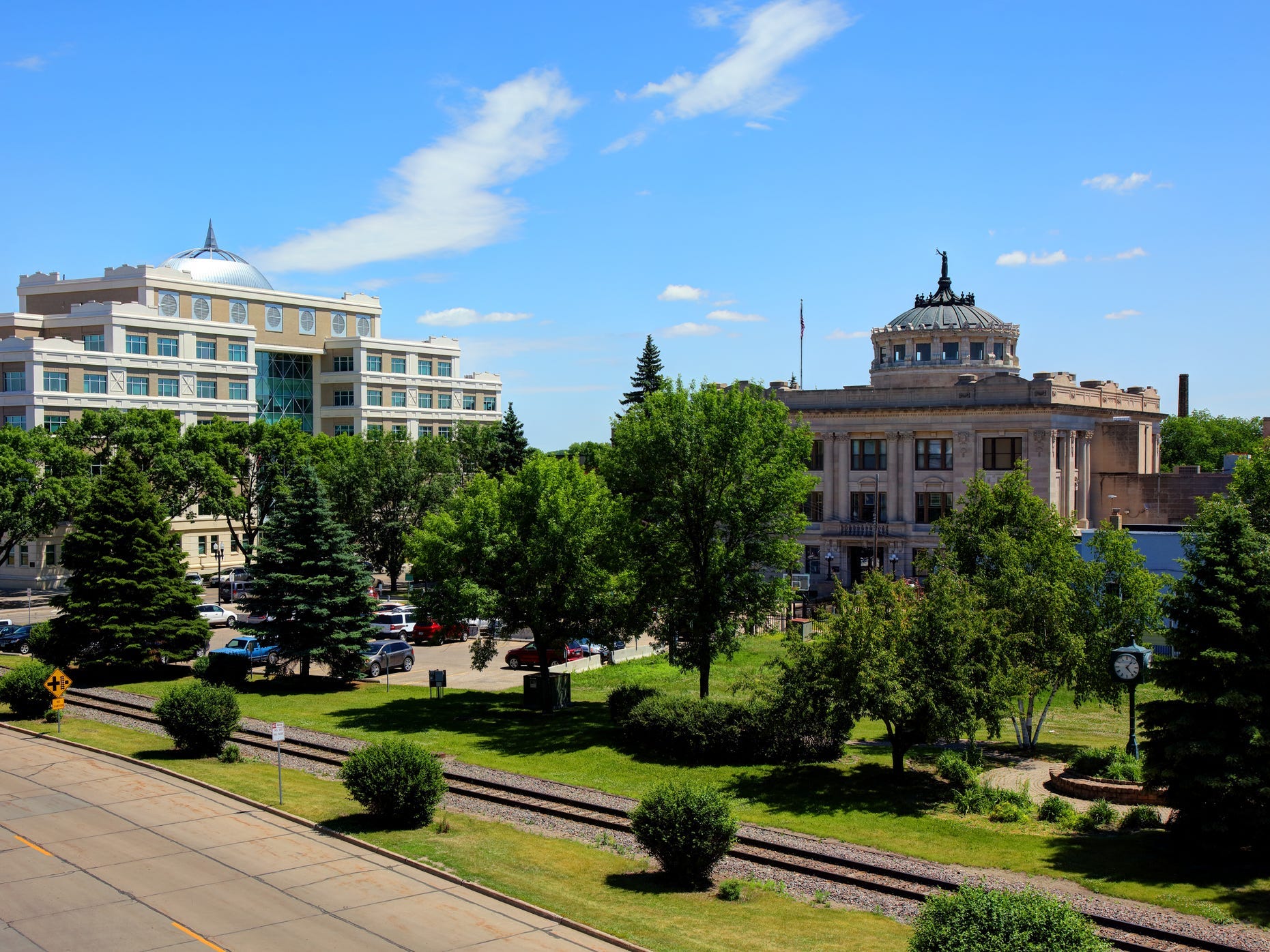A sunny day in downtown Grand Forks, North Dakota, with card parked in front of buildings
