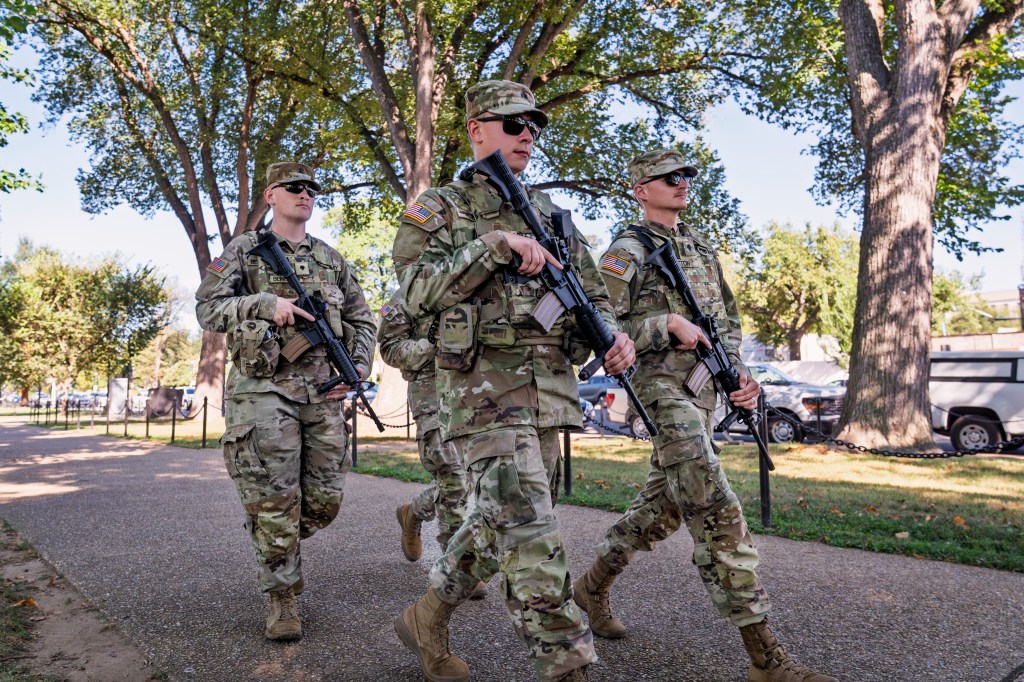 Armed National Guard soldiers walk along Constitution Avenue in Washington, as part of President Donald Trump's order to impose federal law enforcement in the nation's capital, Tuesday, Aug. 26, 2025.